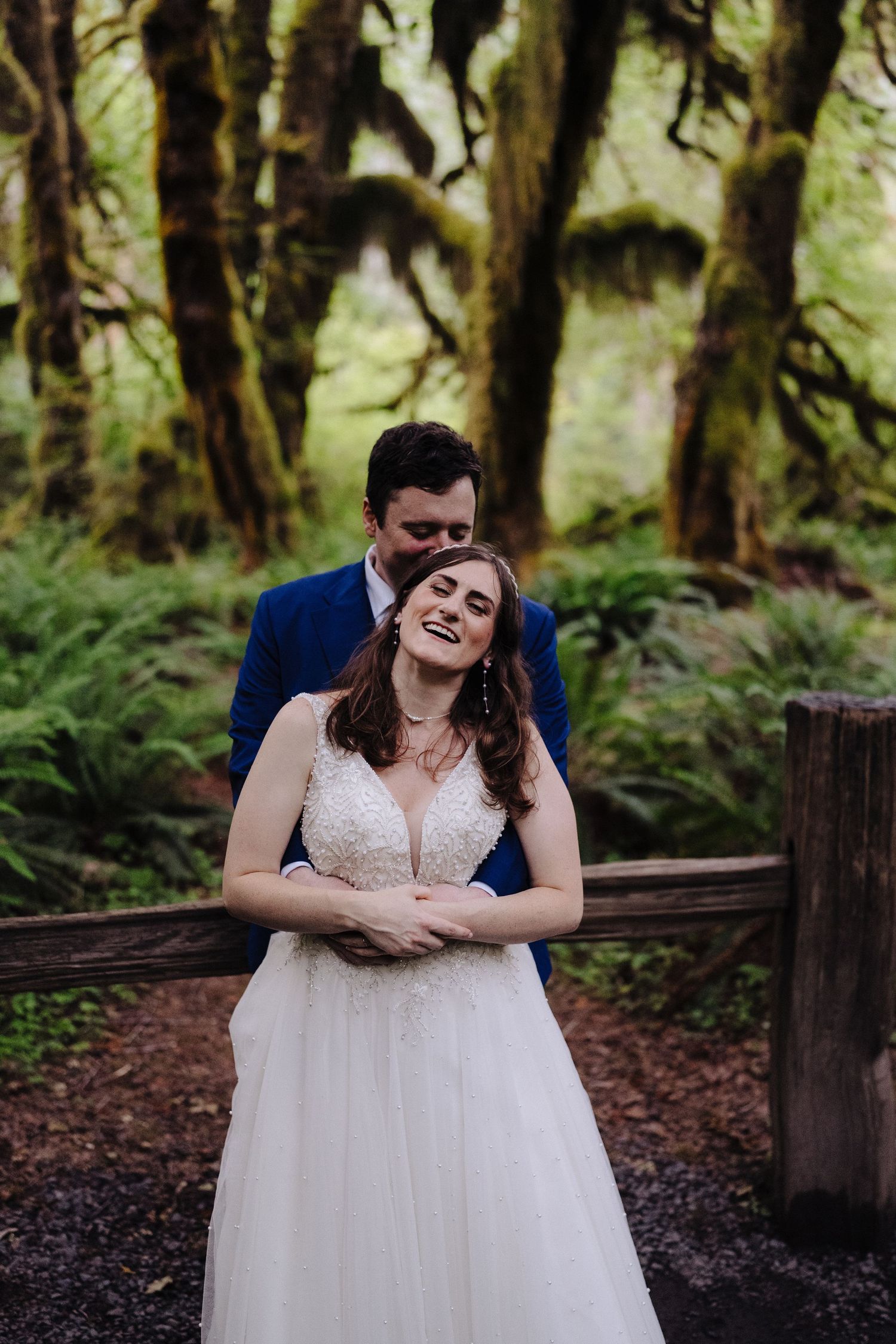 Joyful wedding moment captured in lush mossy forest setting.