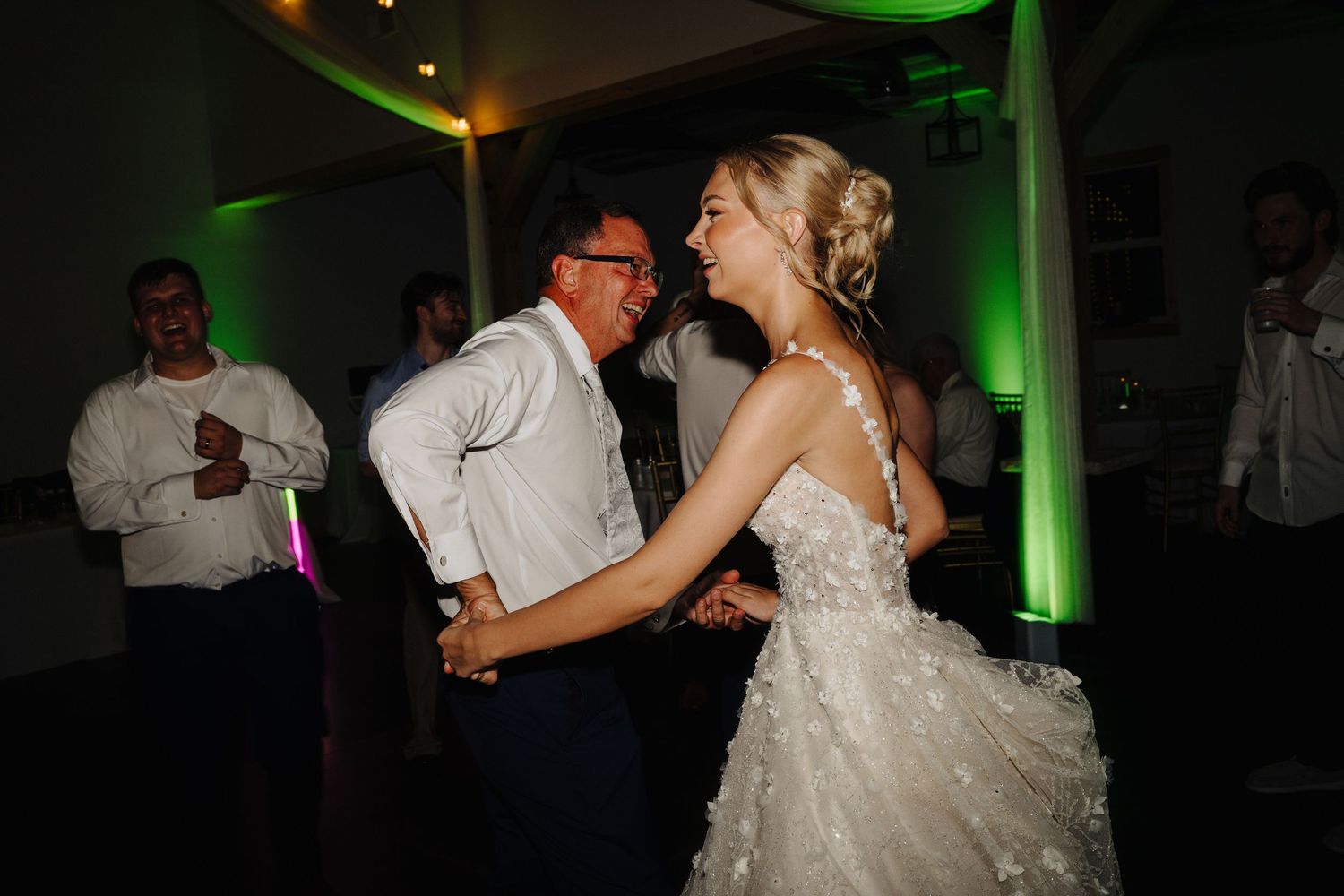 Wedding reception dance floor with green lighting and couples dancing.