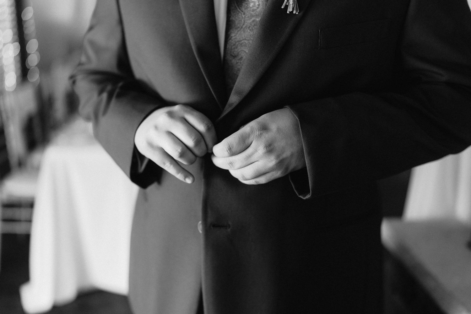 Black and white photo of men in suits reading notes before a wedding ceremony.