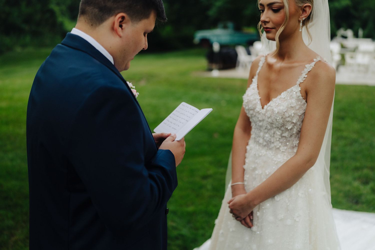Exchange of vows during outdoor wedding ceremony with lush greenery backdrop.