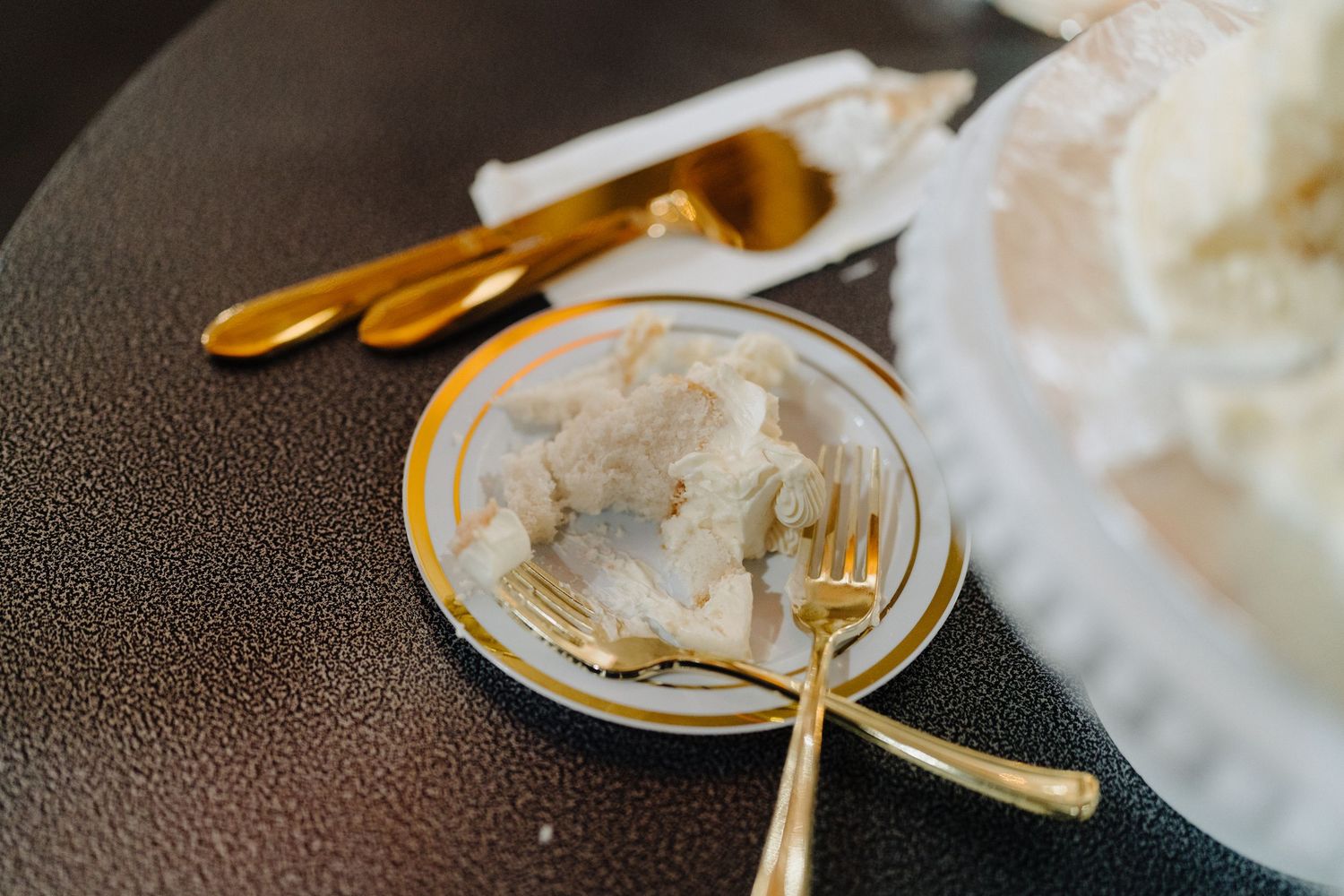 Close-up details of gold utensils and white plates at an elegant wedding place setting.