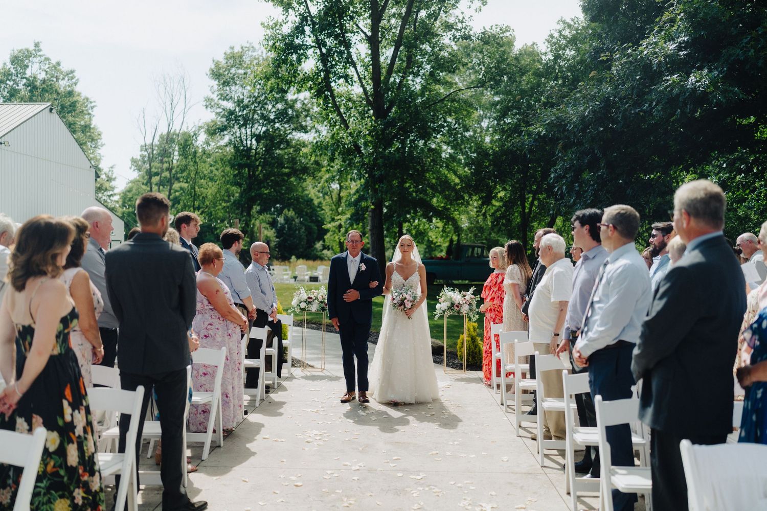 Wedding guests seated in white chairs for an outdoor garden ceremony.