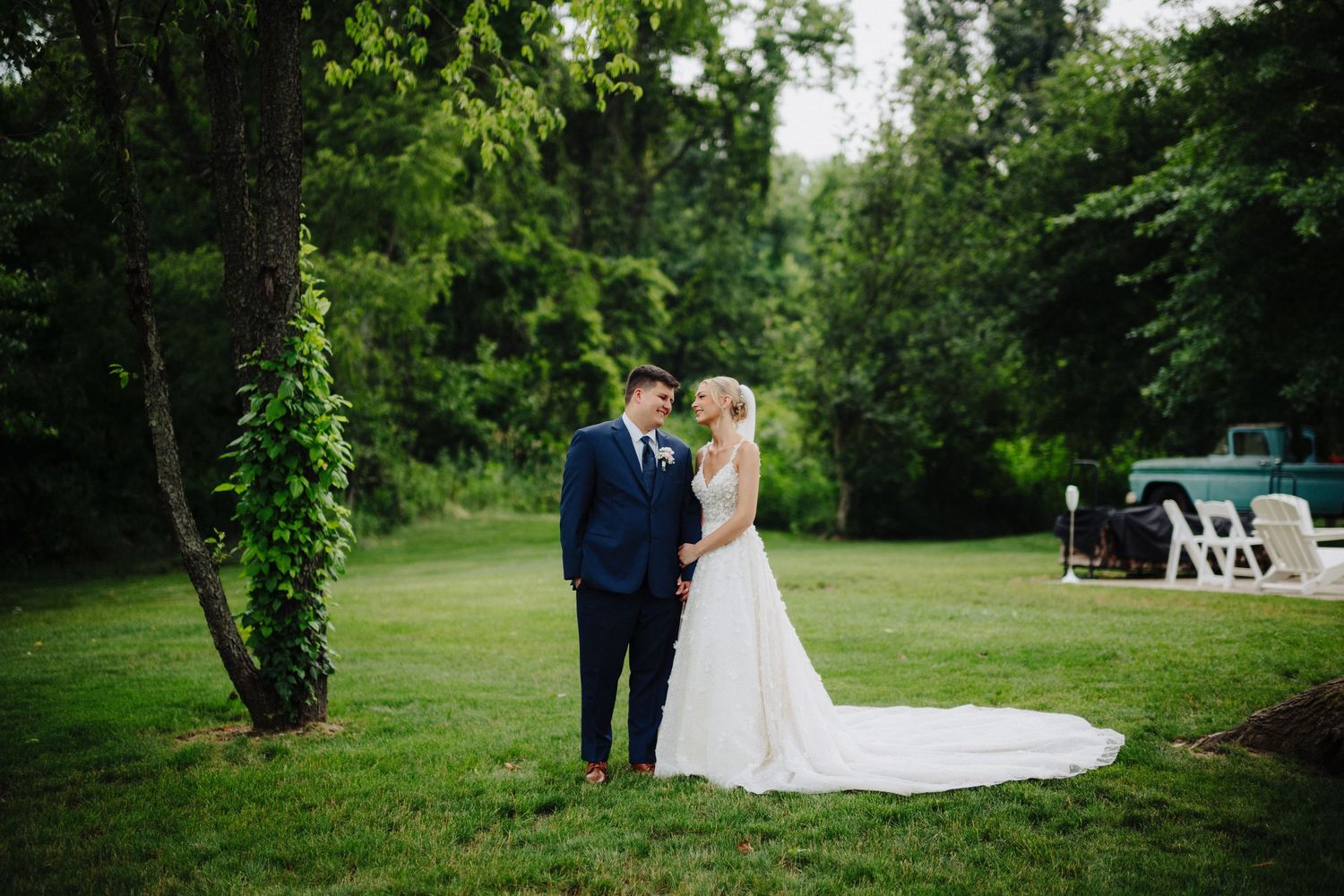 A couple shares an intimate moment in a lush green garden setting during their wedding celebration.