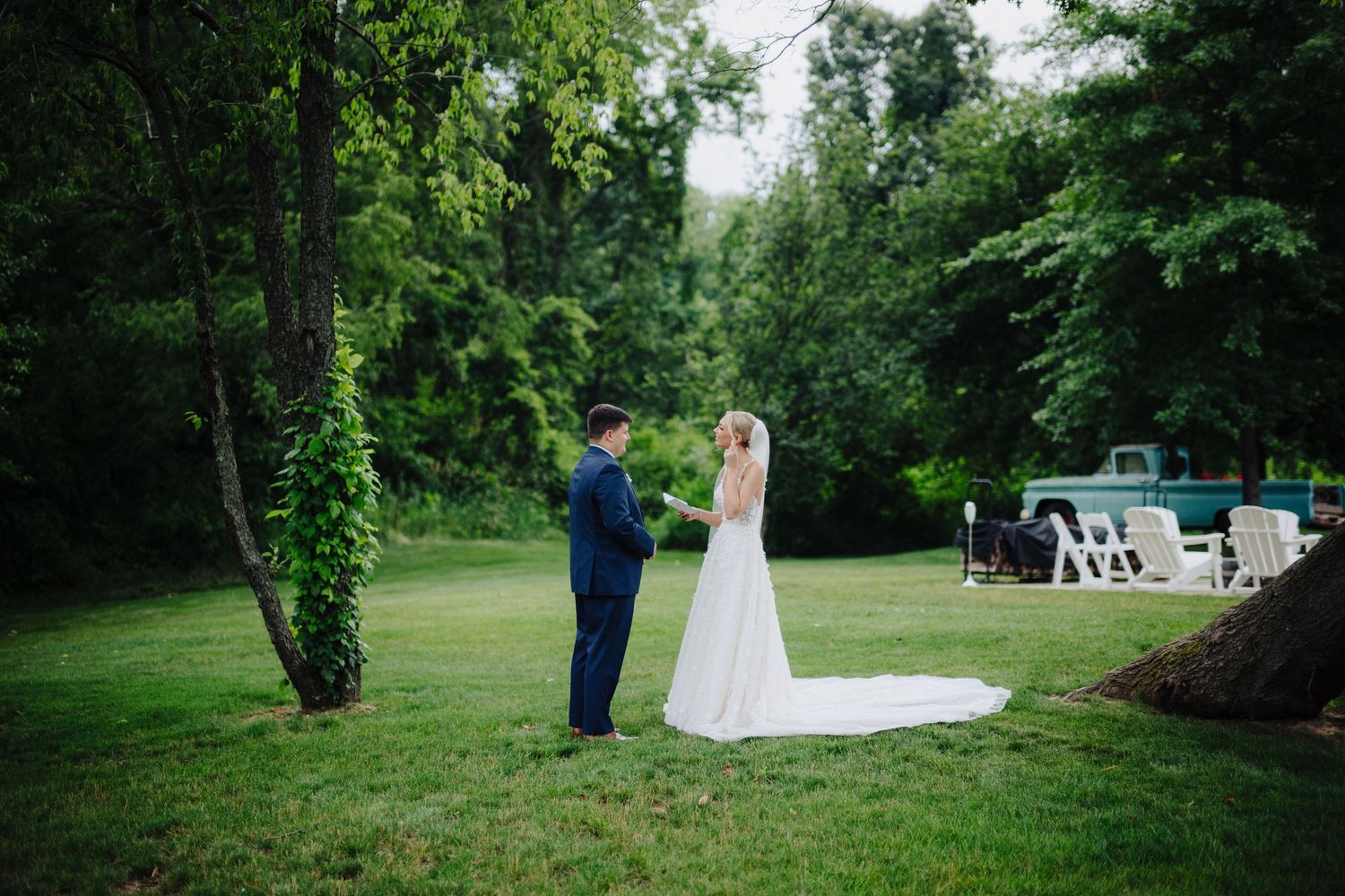A couple takes romantic wedding photos in a lush green garden setting.