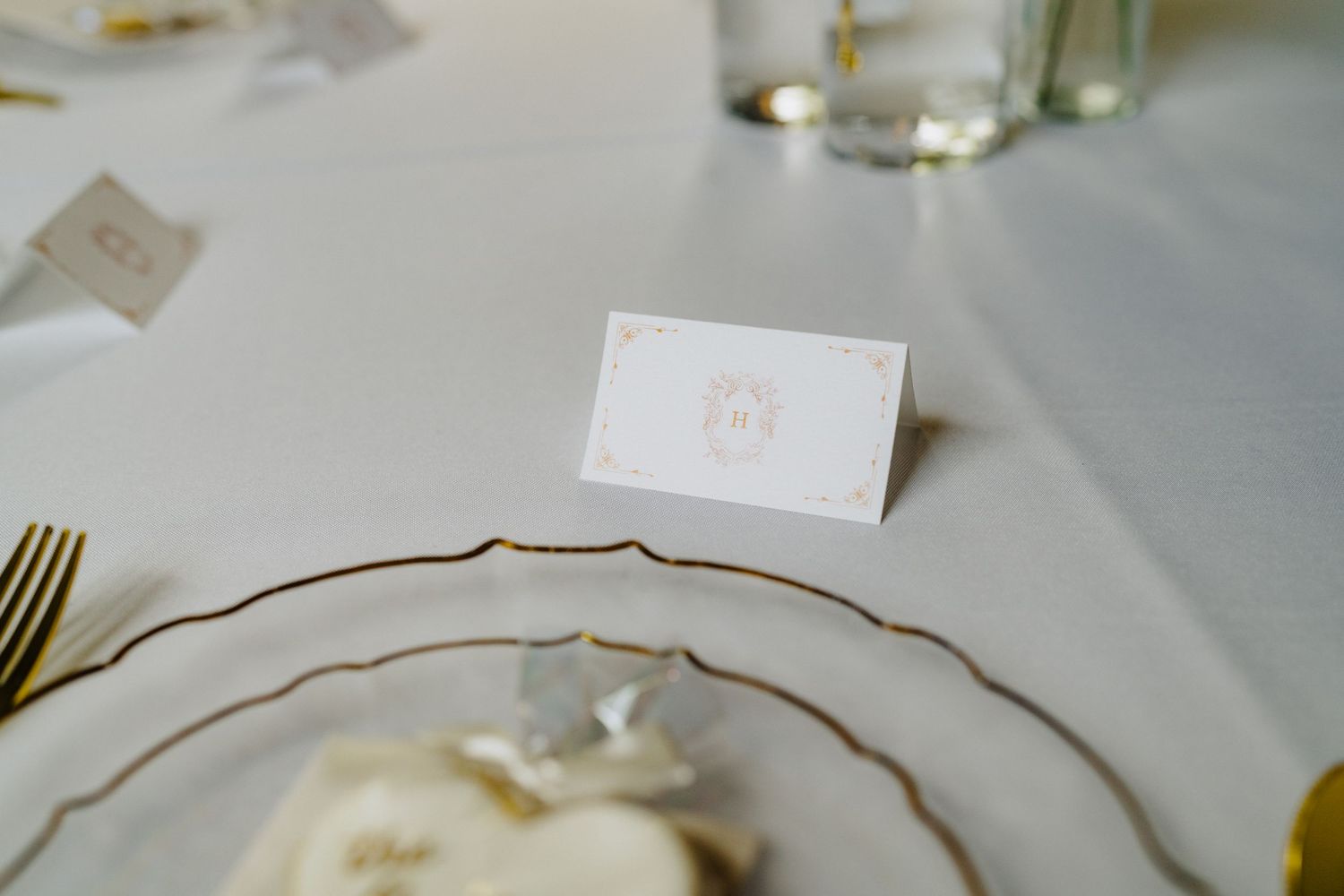 Elegant wedding reception table setting with gold-rimmed plates and place cards.