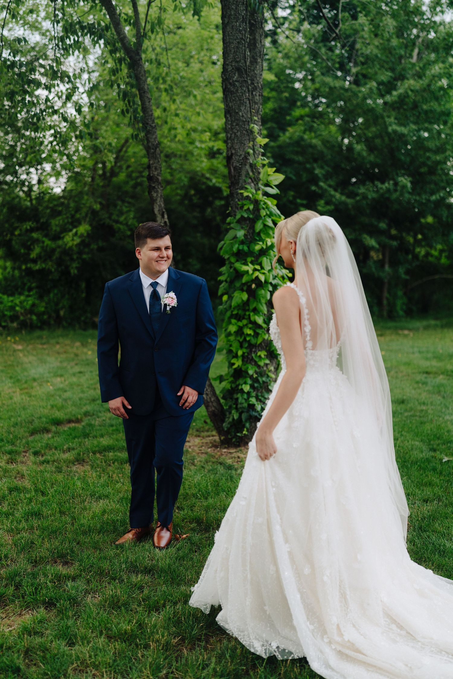 A couple shares a romantic moment outdoors during their wedding ceremony, with lush greenery in the background.