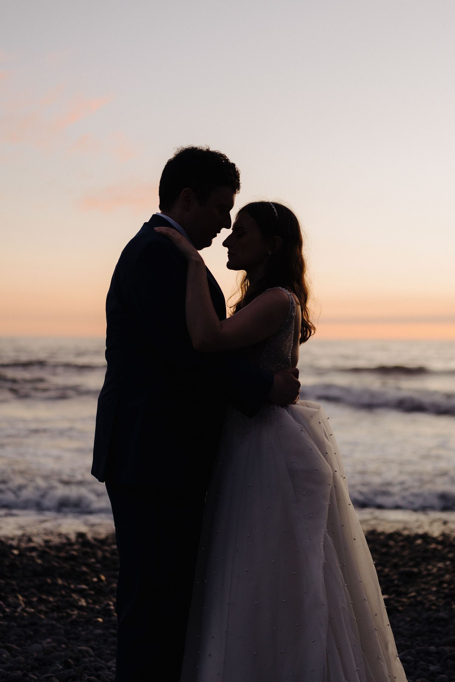 A romantic silhouette of a couple embracing on the beach at sunset.