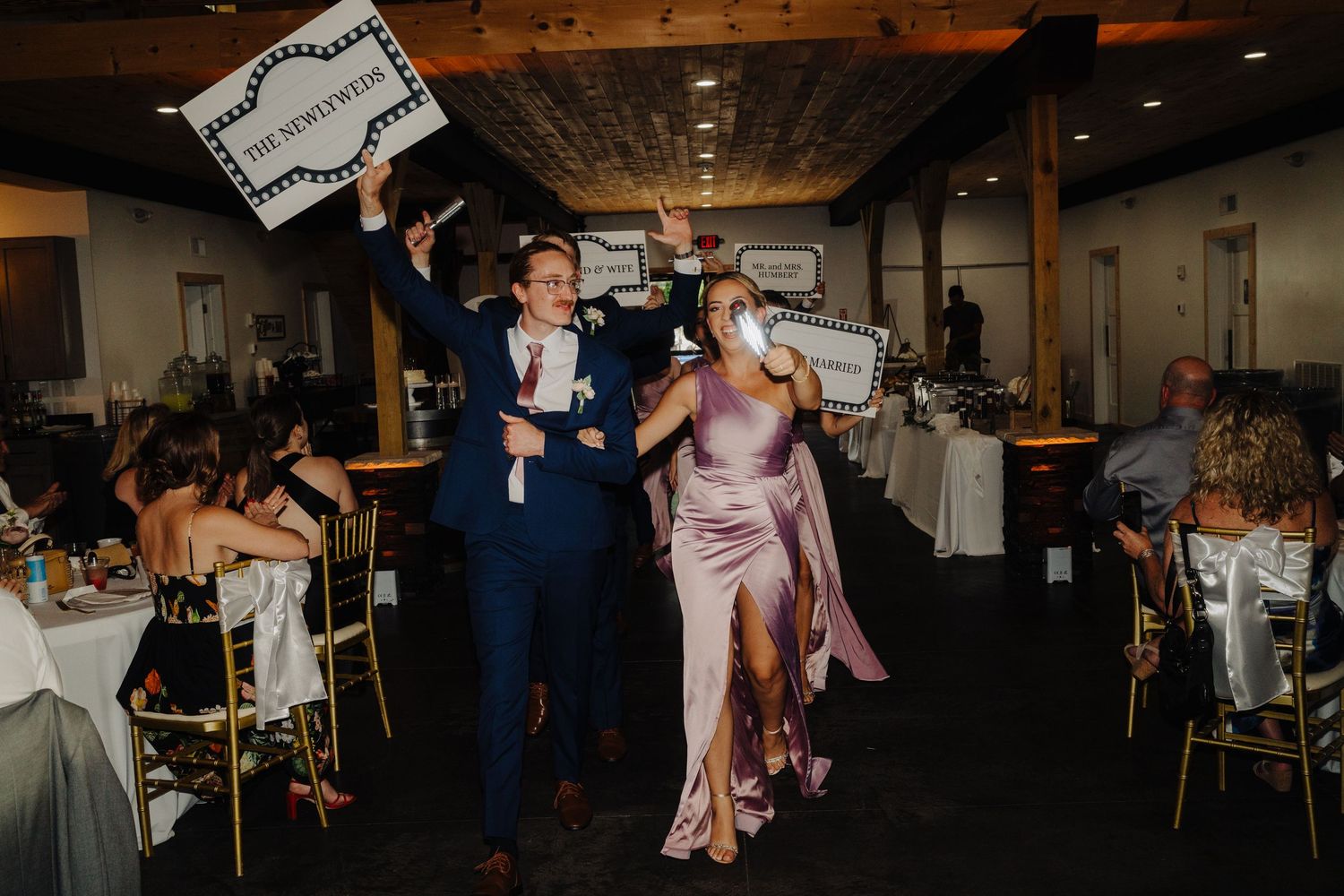 Wedding reception dance floor filled with guests celebrating in a dimly lit venue.