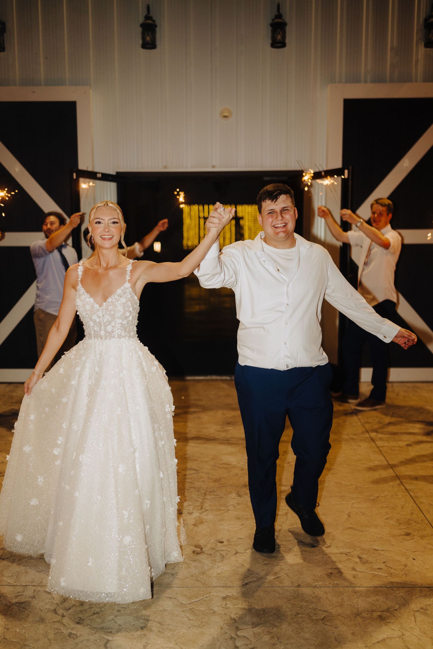 Wedding guests and couple dancing joyfully in a rustic barn reception venue.