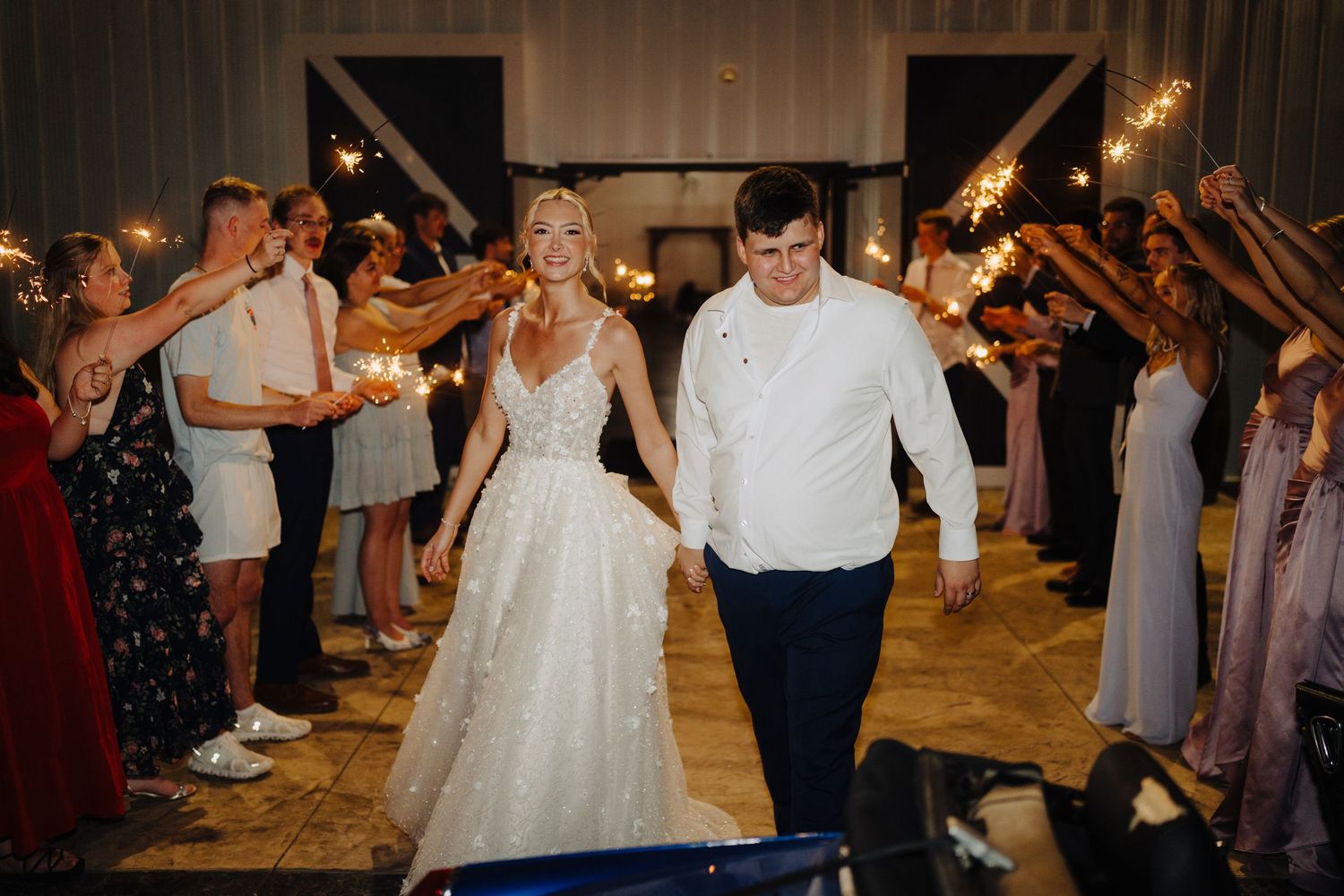 Wedding celebration finale with guests holding sparklers as couple dances.