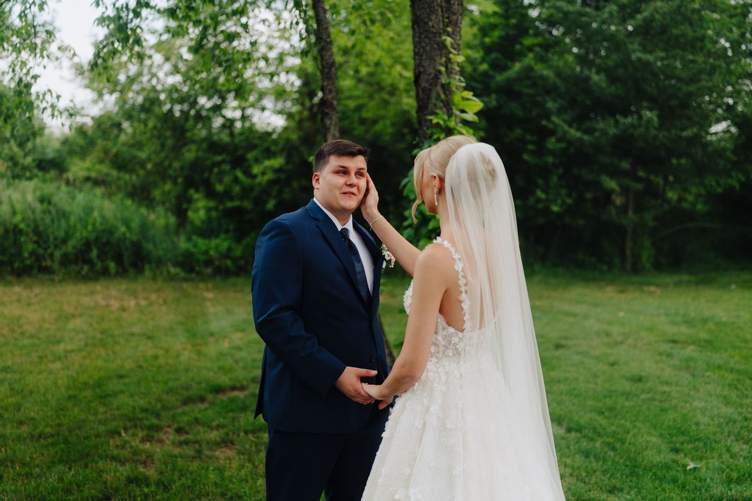 Intimate first look moment between couple in front of rustic white barn.