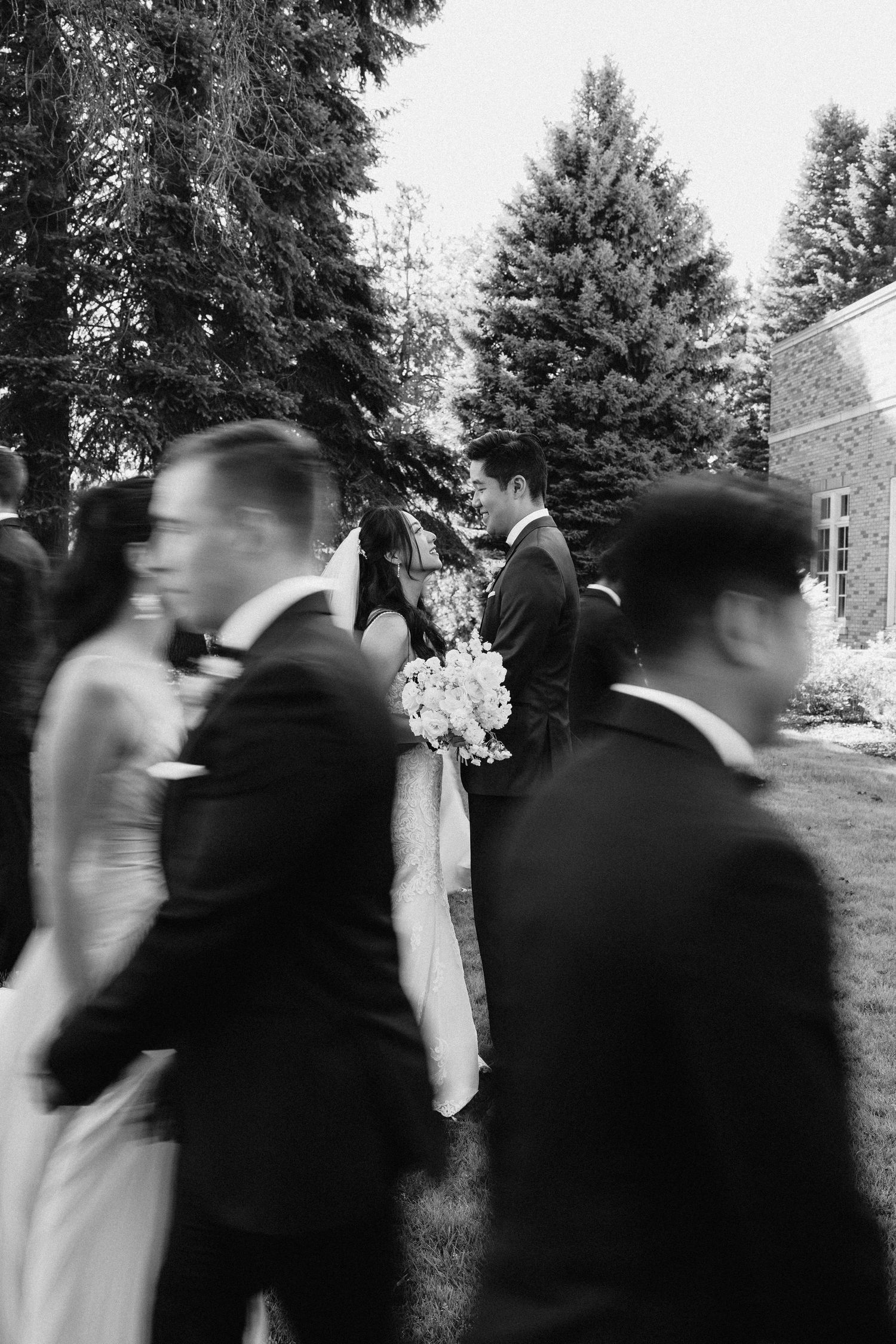 Black and white candid of wedding guests mingling at outdoor reception.