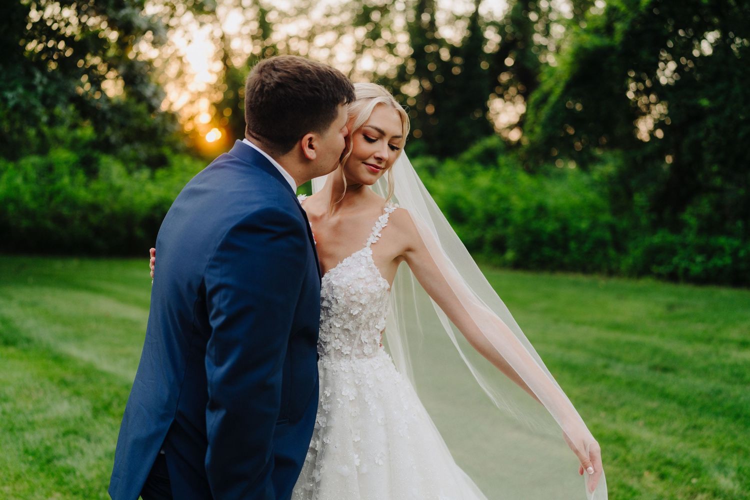 A couple shares an intimate moment on their wedding day in a lush green garden setting.