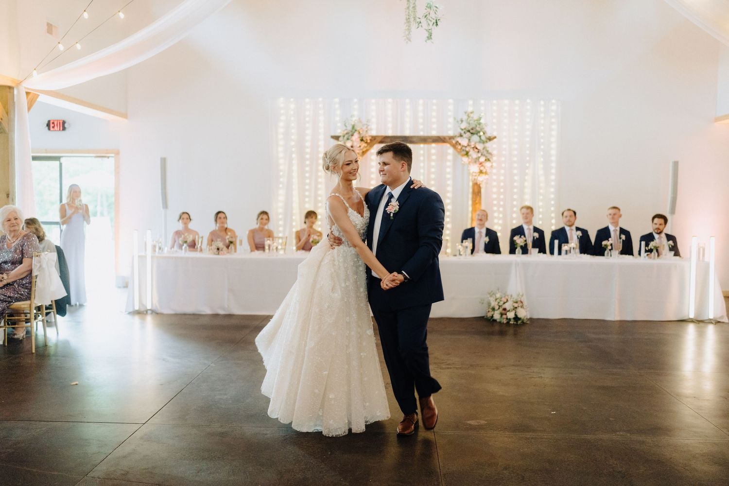 A bright and airy modern wedding venue with white walls and natural light streaming through large windows.