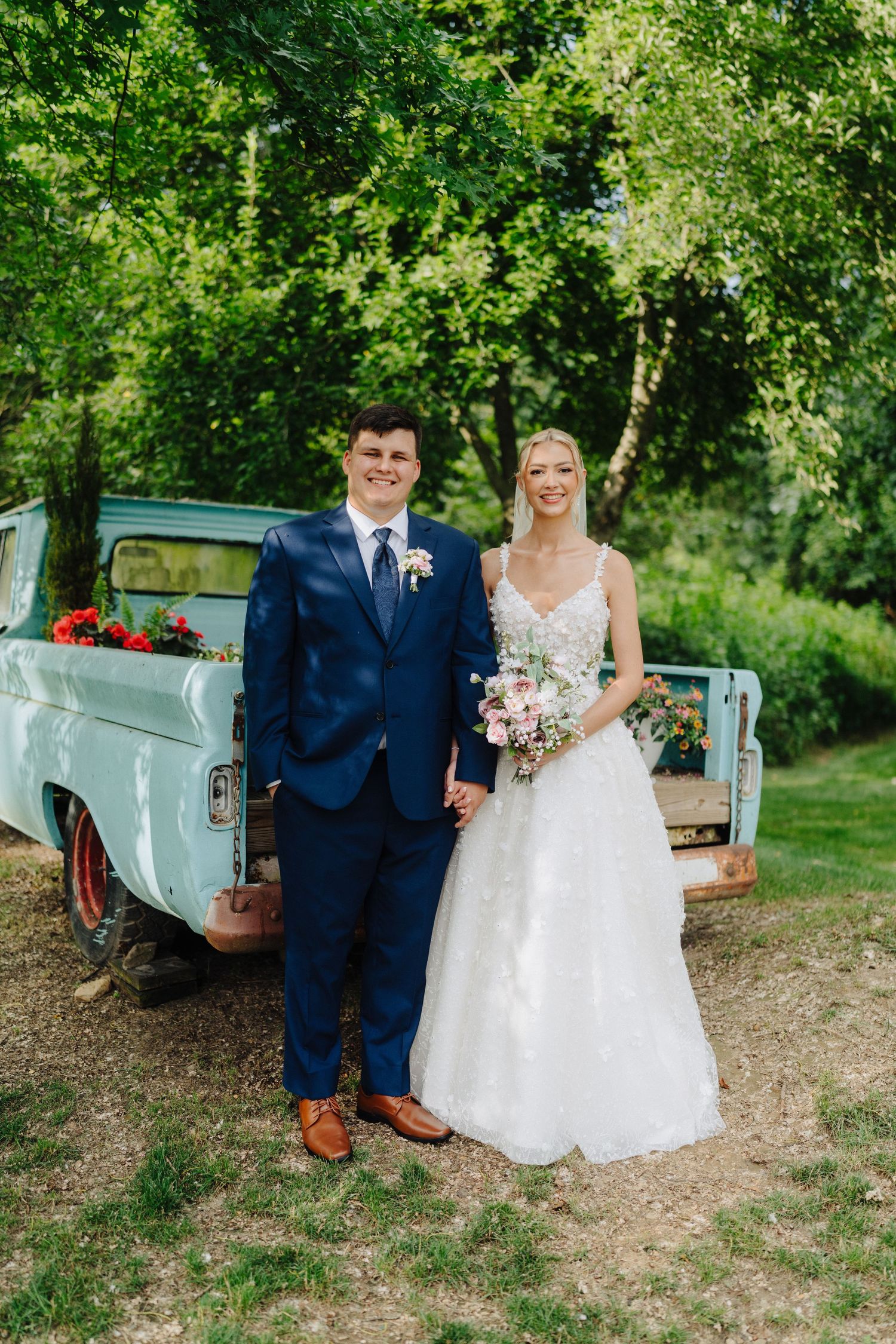 A vintage mint green pickup truck serves as a backdrop for wedding photos on a sunny day.
