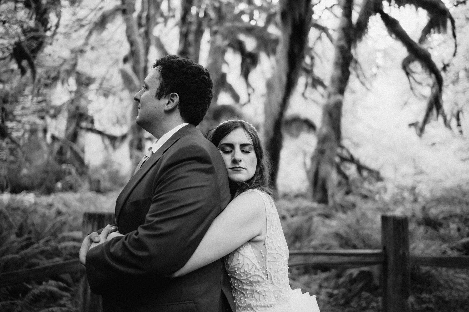 A black and white intimate wedding portrait captured in a mystical forest setting.