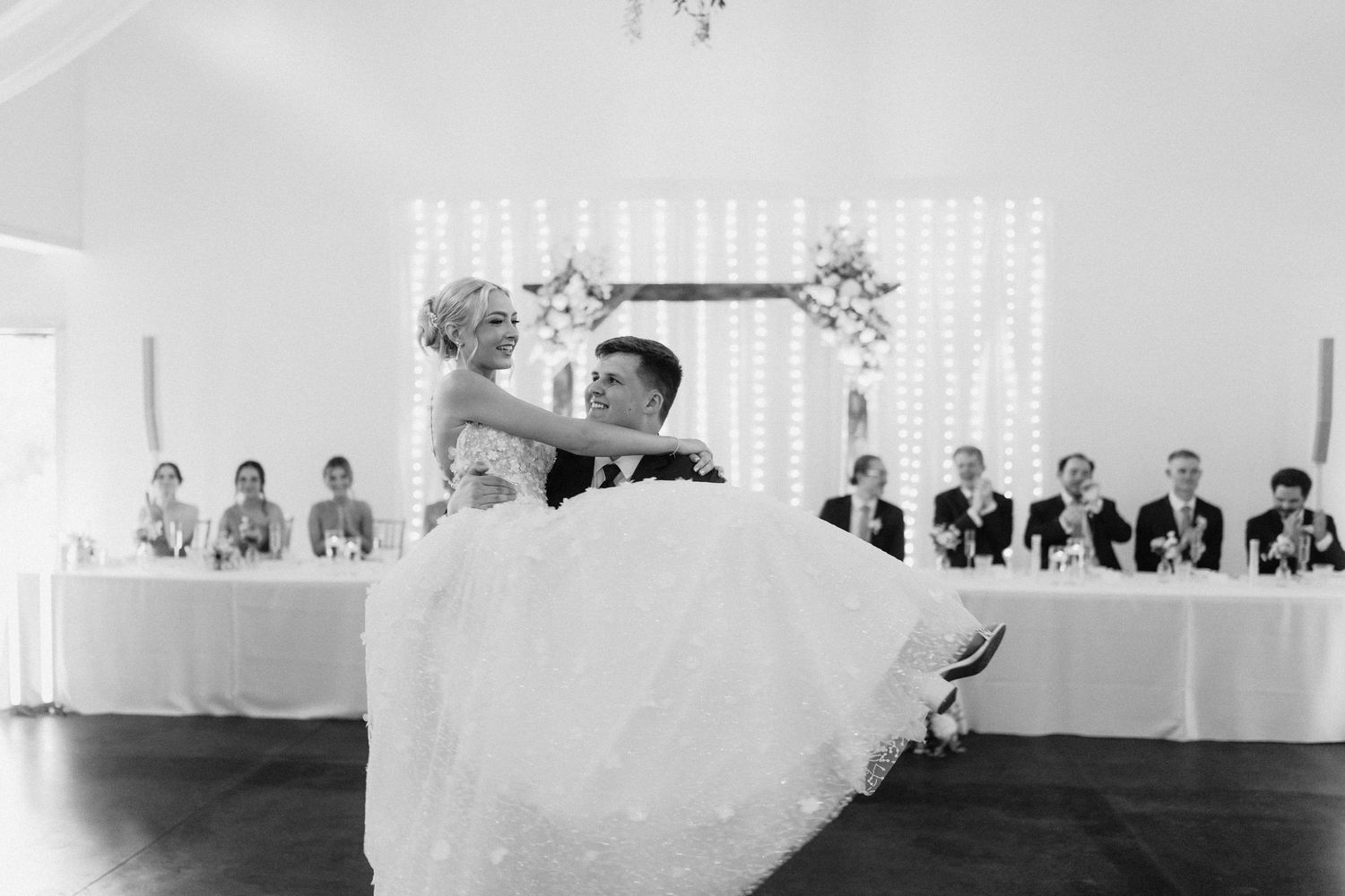 Black and white photo of wedding reception with white draping and tables set for dinner.