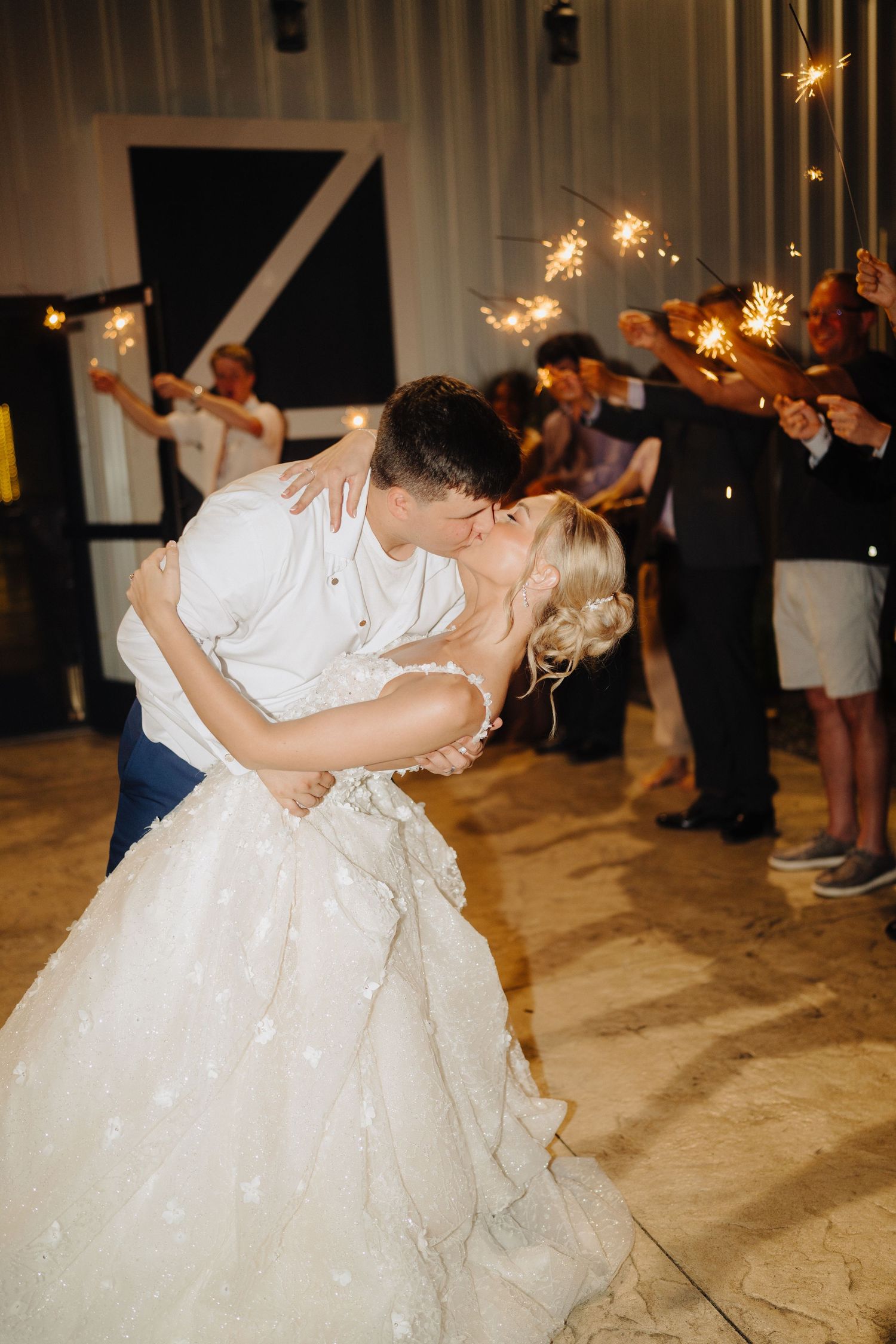 Wedding couple shares a romantic dance moment surrounded by sparklers and guests.