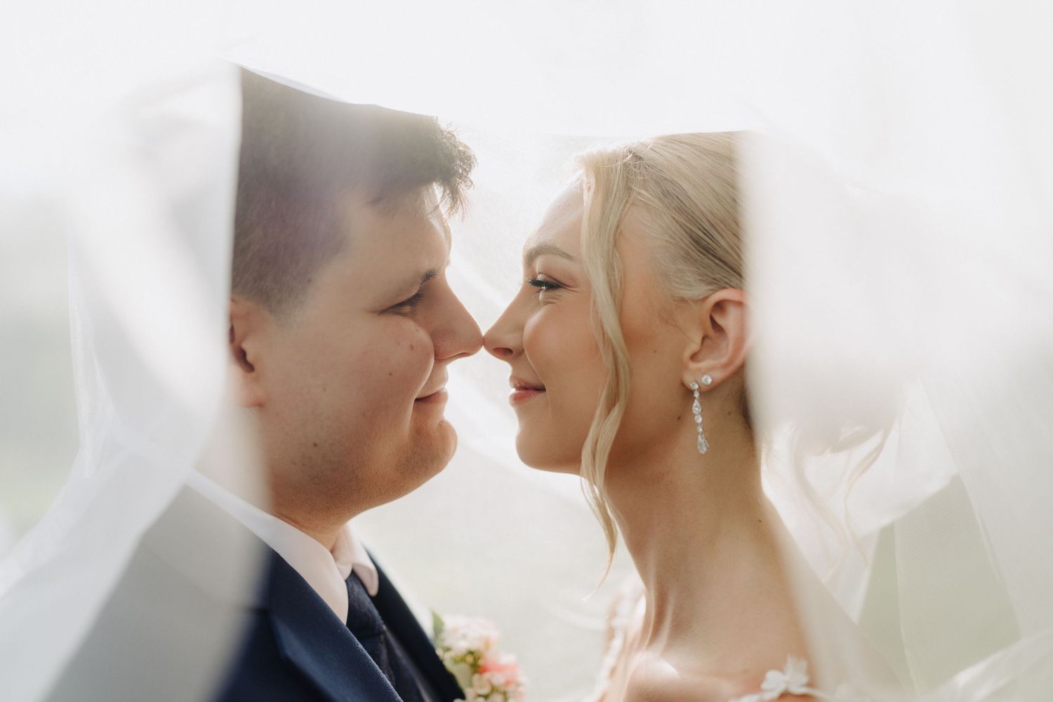 Romantic close-up of newlyweds sharing an intimate moment under bridal veil.