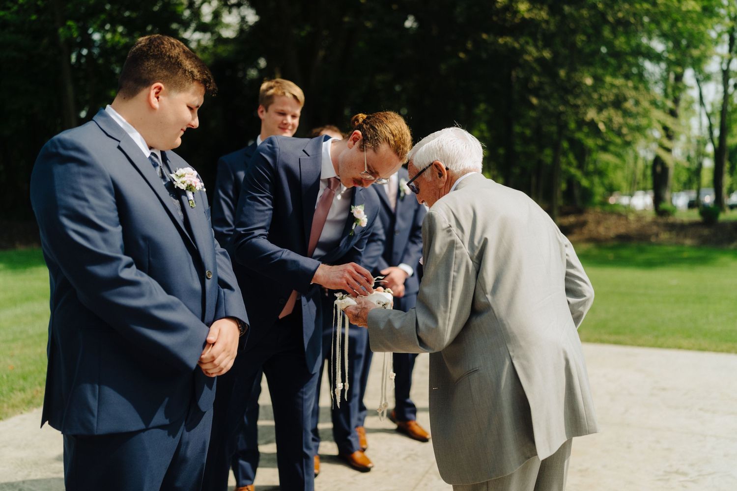 Wedding party members in formal attire gather outdoors before ceremony.