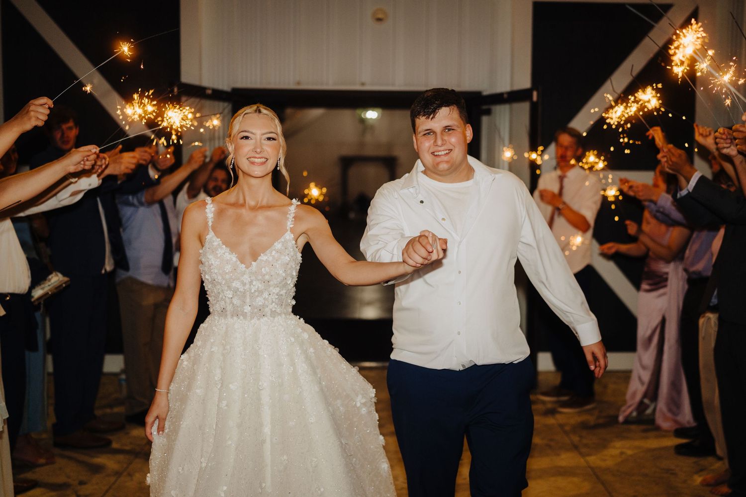 Wedding guests holding sparklers create a magical exit tunnel during an evening celebration.