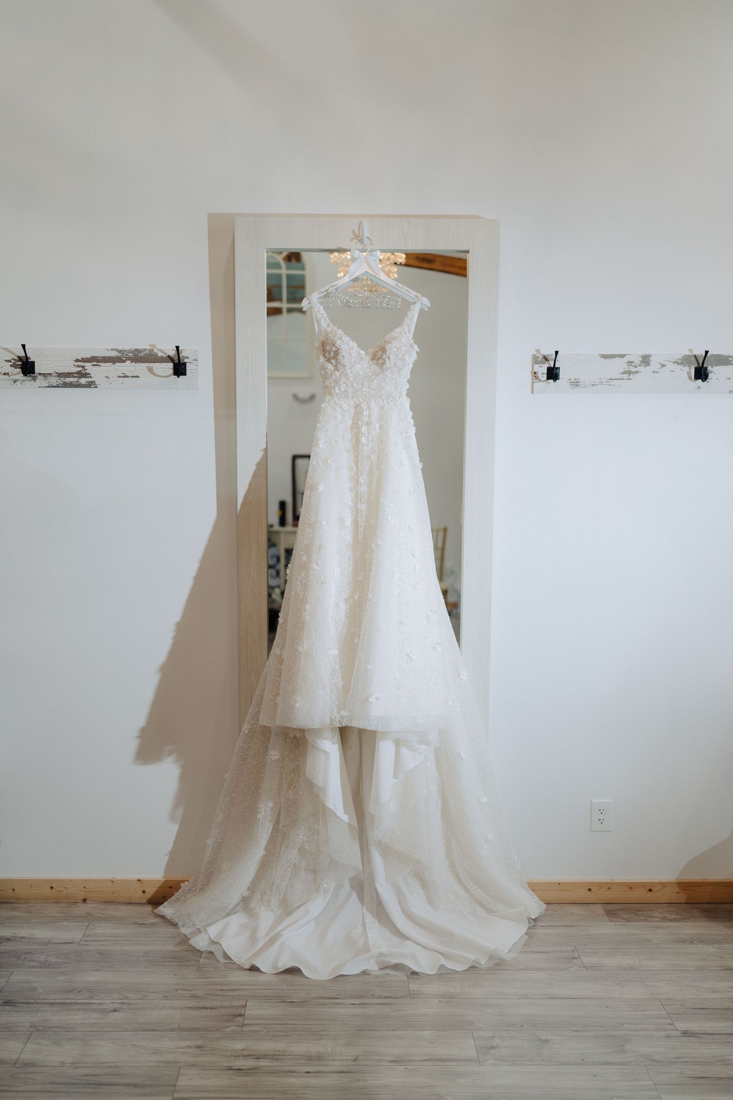 Elegant white lace wedding dress with train hanging in a dressing room mirror.