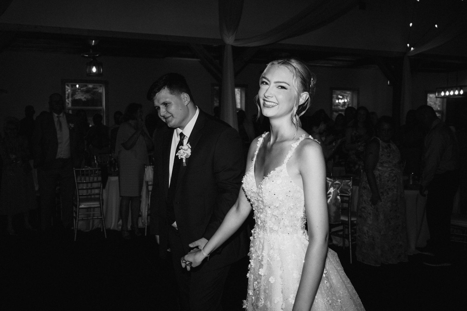Black and white candid shots of wedding guests dancing and celebrating on a dimly lit dance floor.