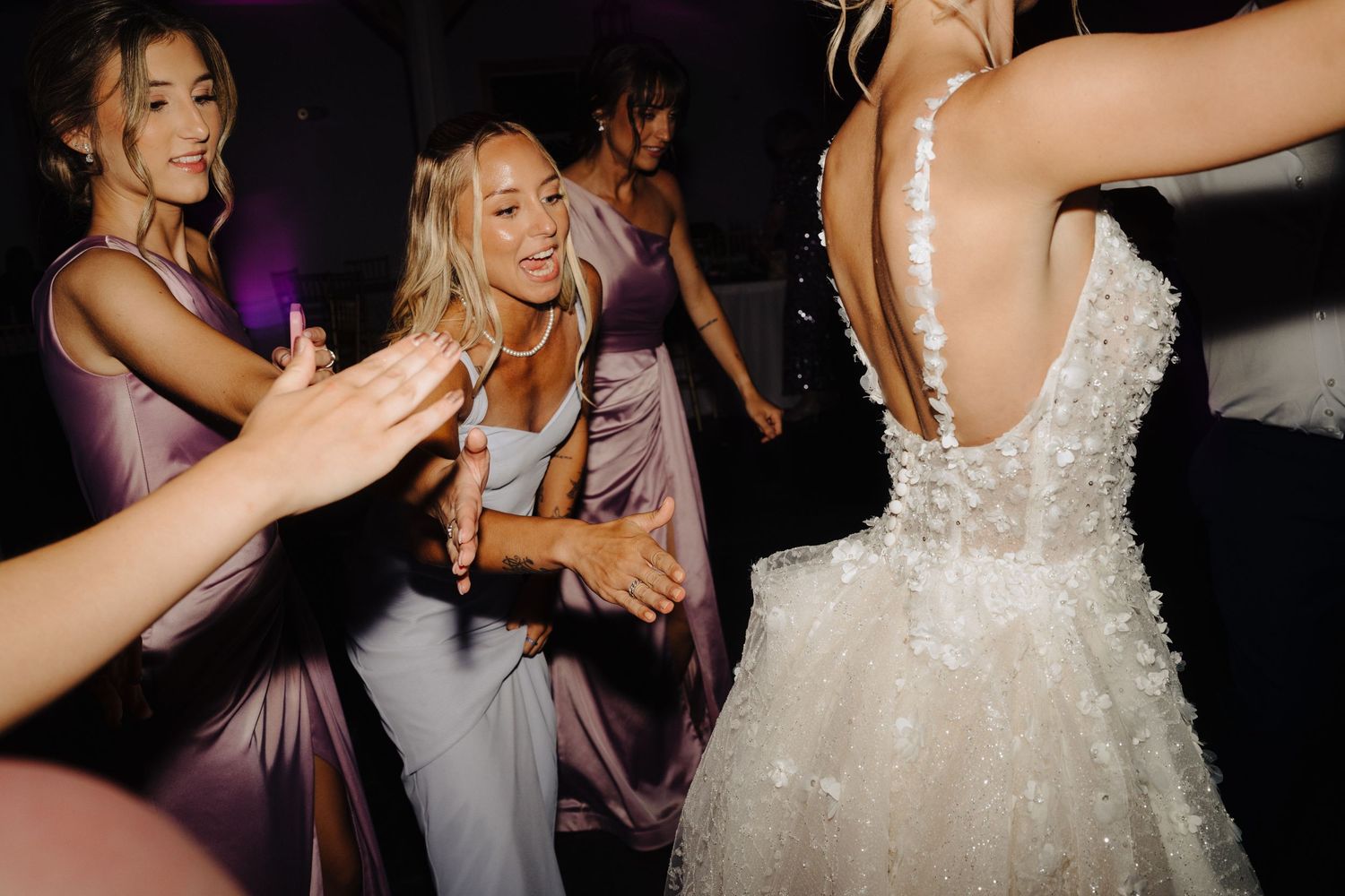 Wedding reception guests dancing and celebrating on a dark dance floor.