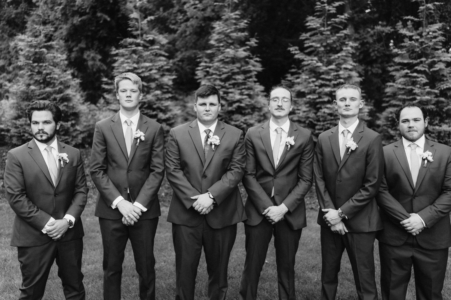 Groomsmen in dark suits pose together for formal wedding photo.