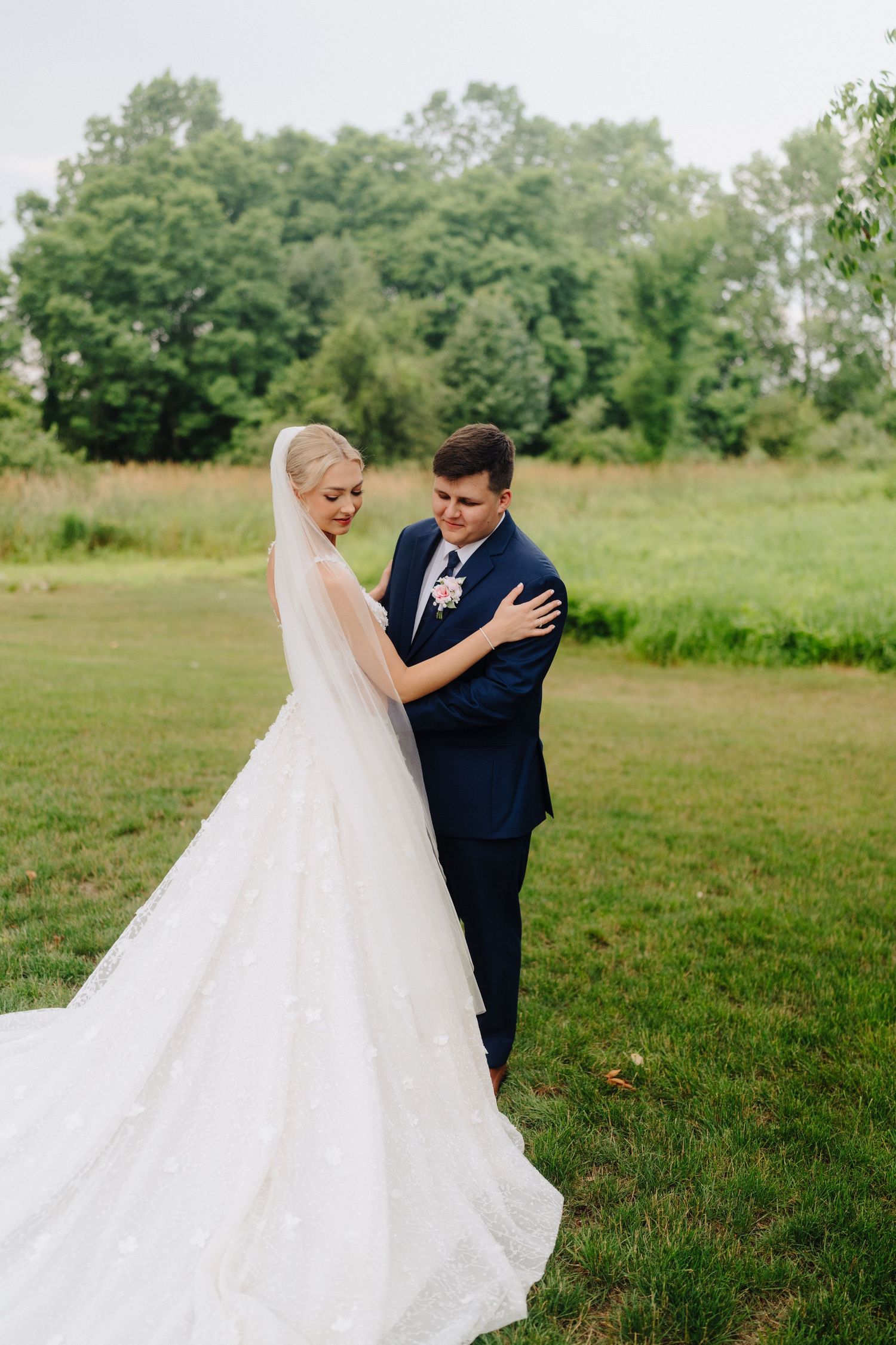 Couple shares emotional first look moment in a lush green outdoor setting.