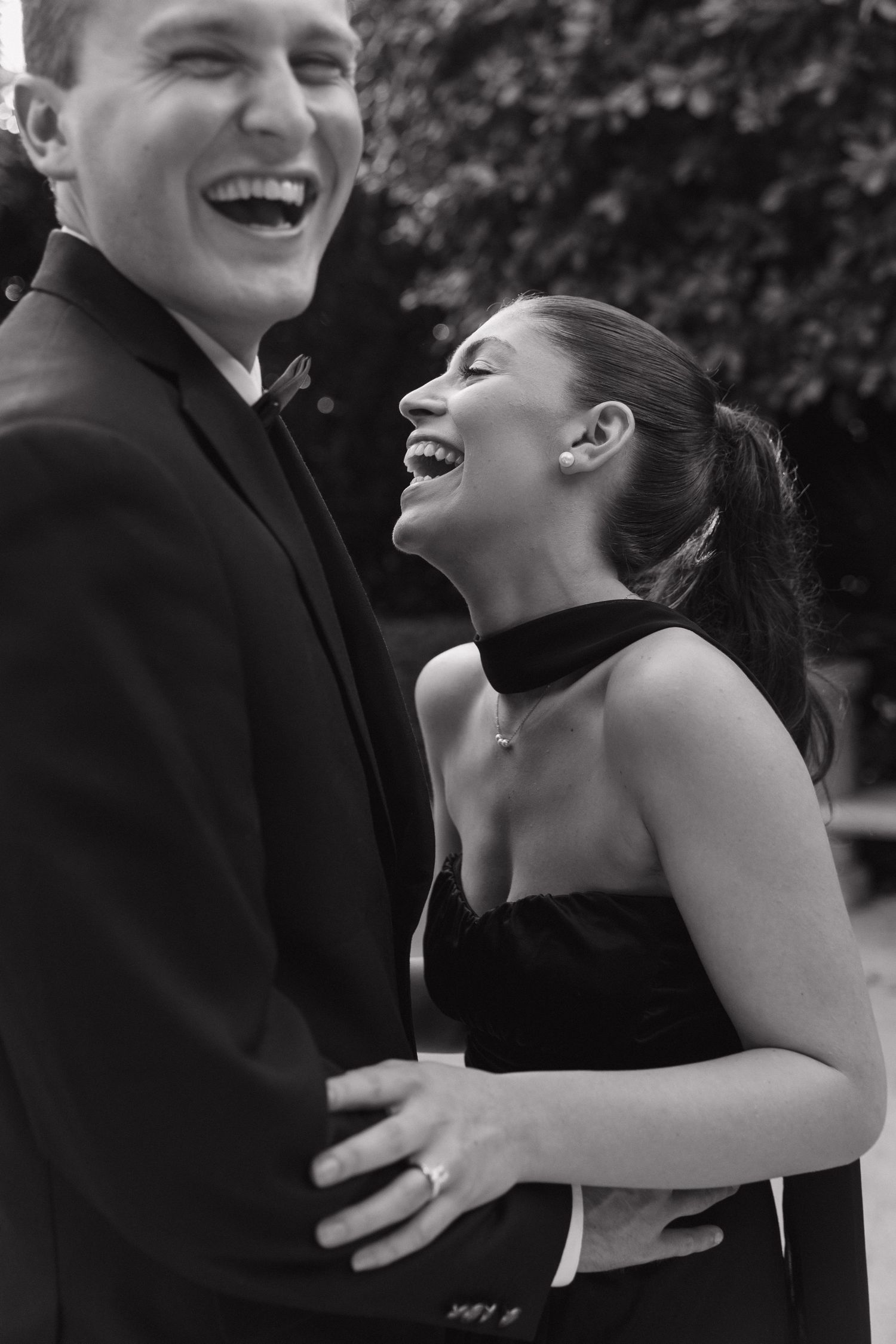 A candid black and white photo of a couple laughing together at a formal event.