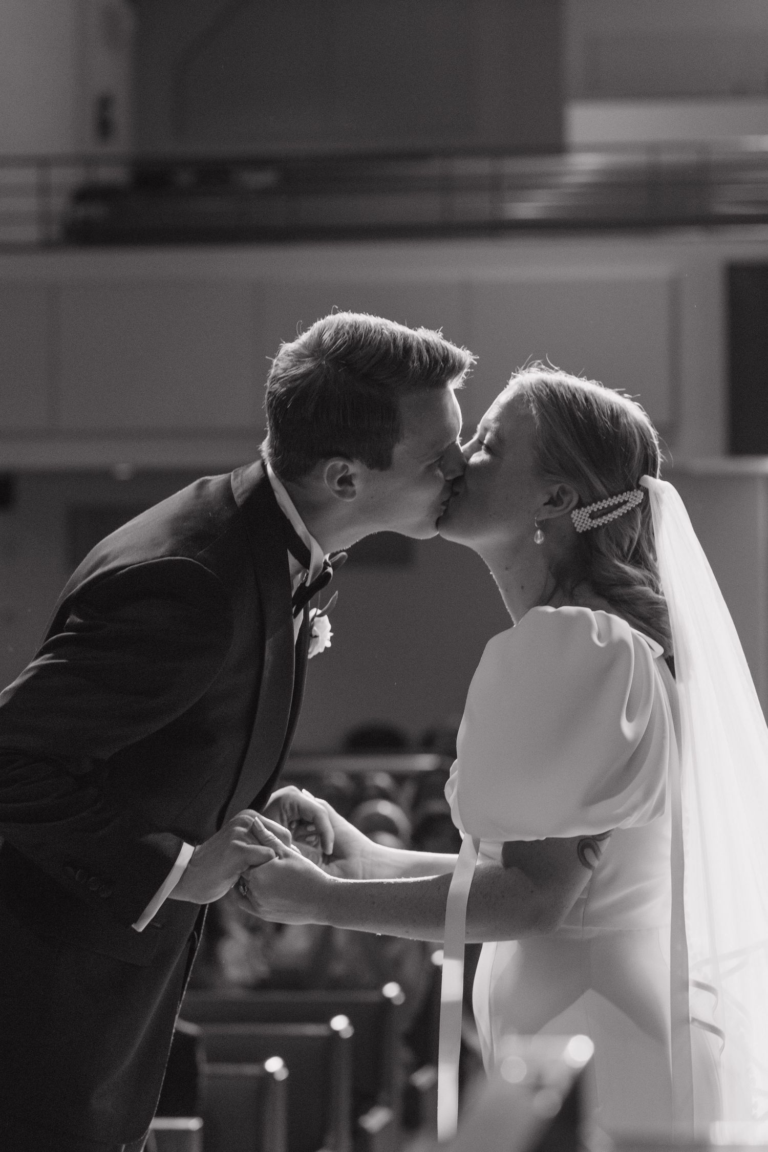 A romantic black and white sequence of four photographs showing a couple's first kiss during a wedding ceremony.