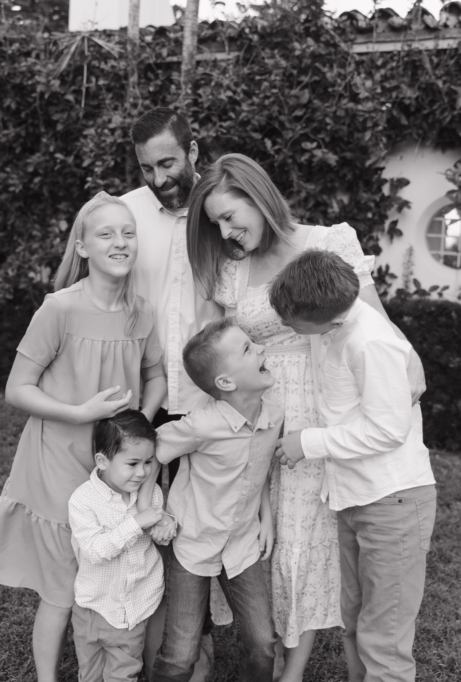 Family sharing joyful moments together against an ivy-covered wall outdoors.