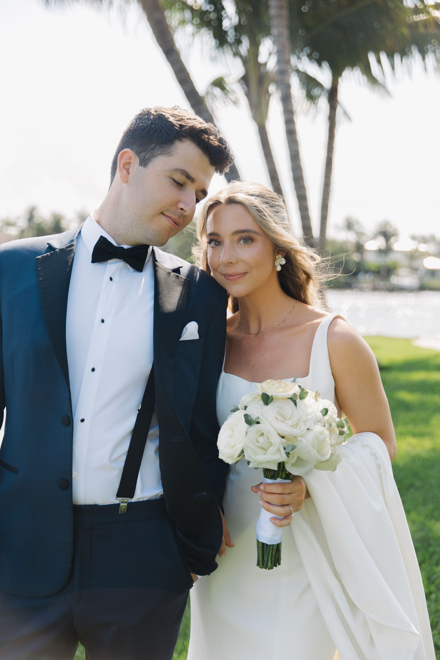Romantic black and white wedding photo series of newlyweds in formal attire with white floral bouquet on tropical grounds.