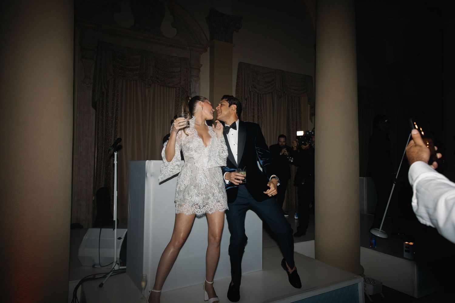 Couple in formal attire dancing together at an evening event while photographer captures the moment.