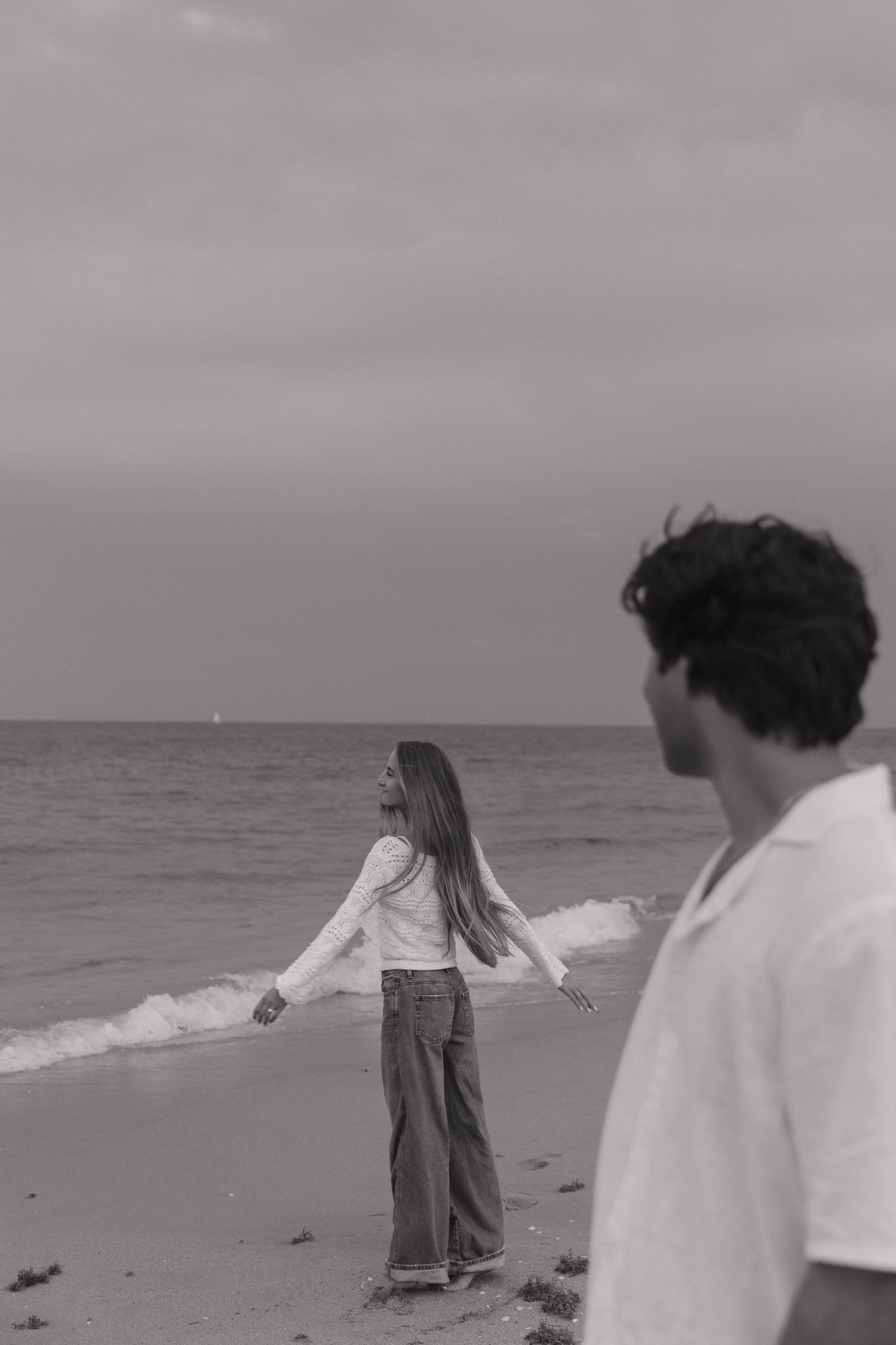 Black and white sequence of people walking along a beach shoreline.