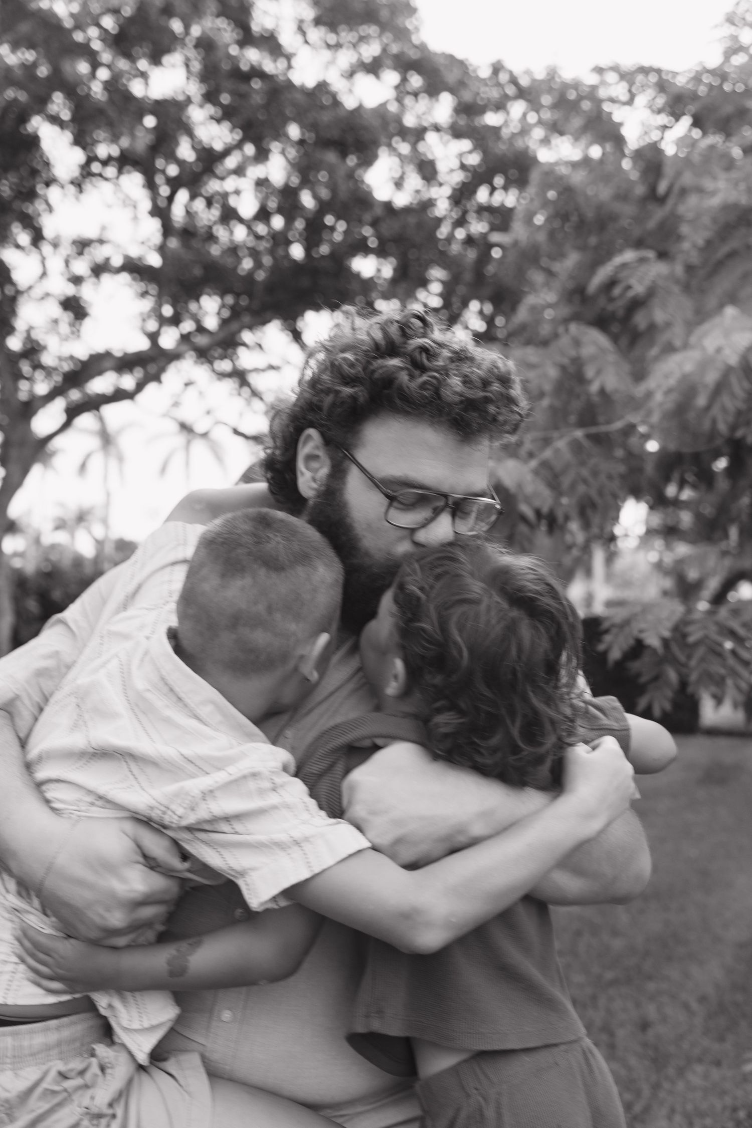 A black and white photo series shows two people sharing a tender embrace outdoors in a park setting.
