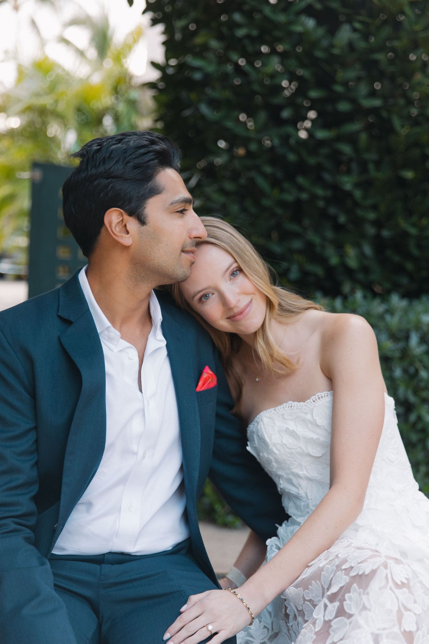 A romantic wedding couple shares an intimate moment in a garden setting.
