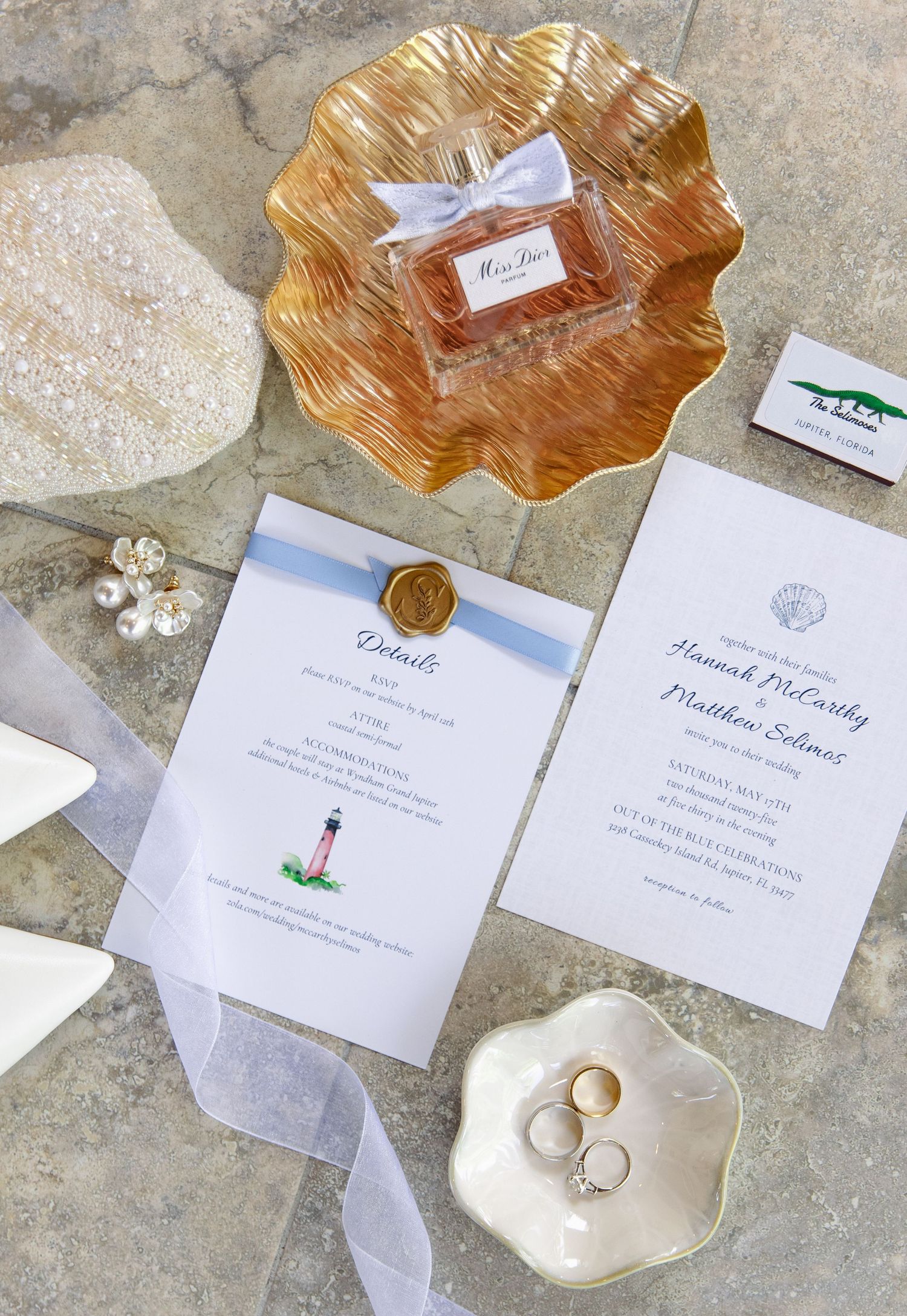Wedding invitations and stationery laid out on a stone surface with gold decorative shells and delicate details.