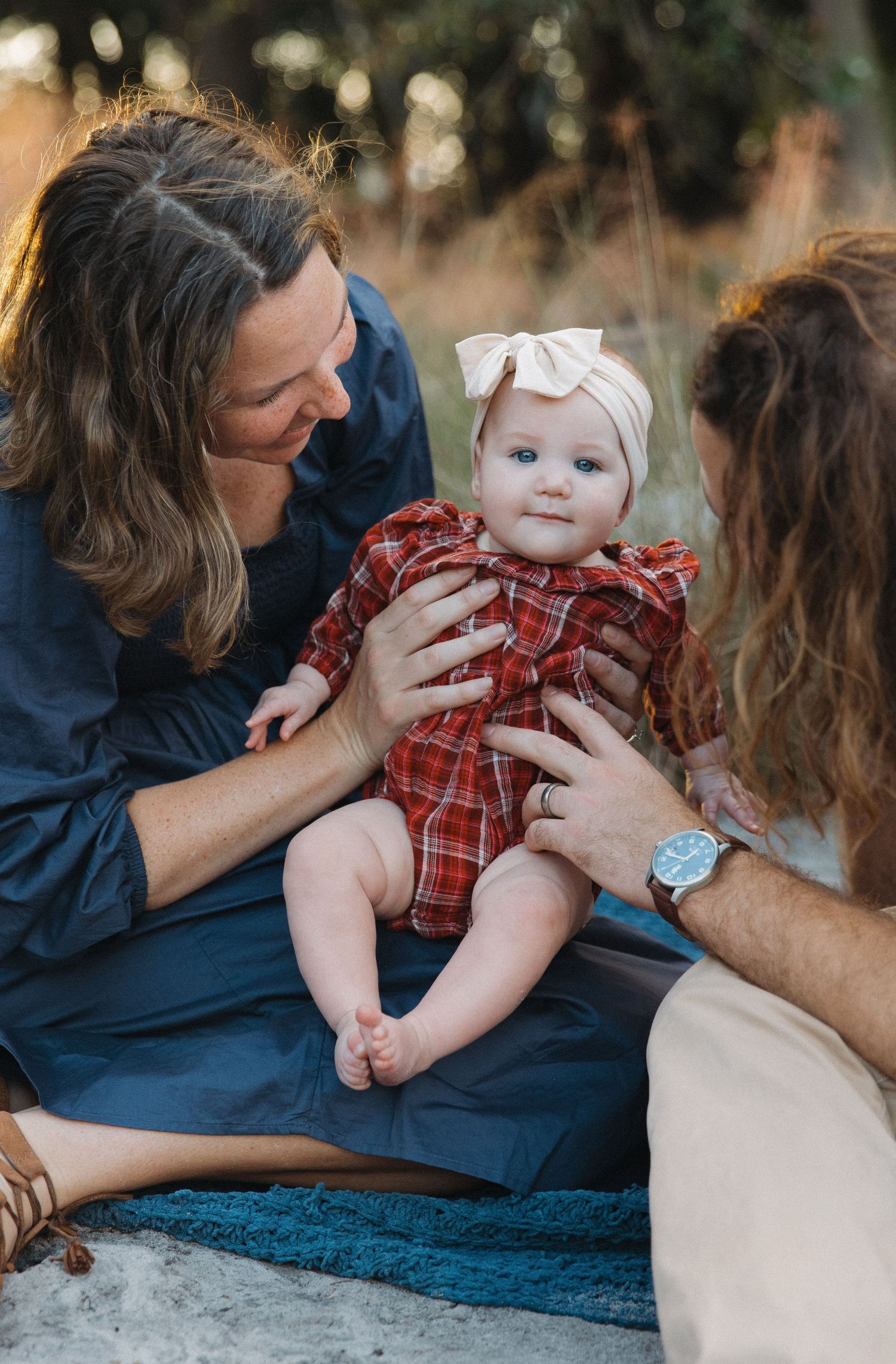 A series of candid photos showing tender family moments on a blue blanket outdoors.