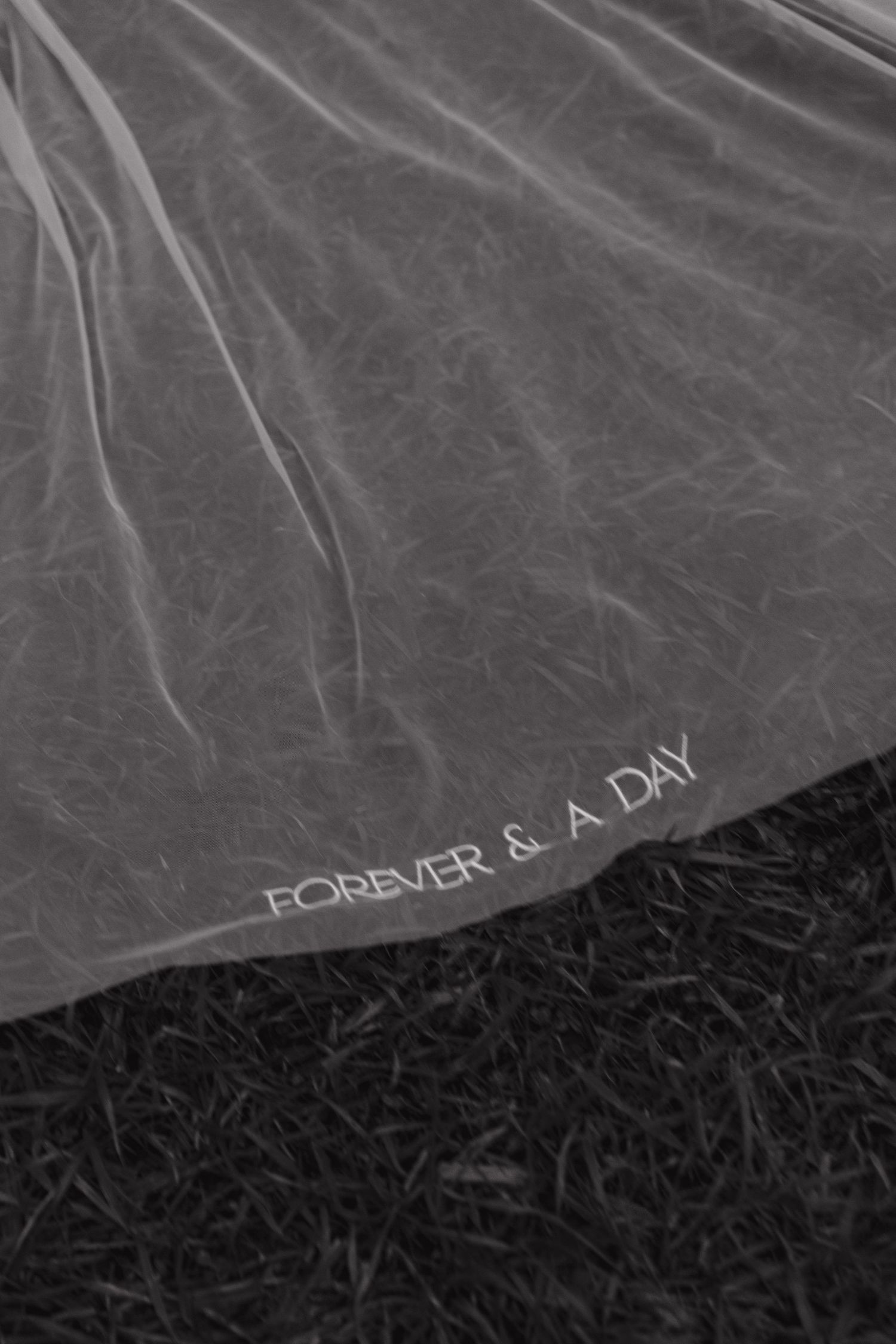Black and white abstract image with grainy texture showing partial text 'FOREVER & A DAY' on a dark background.