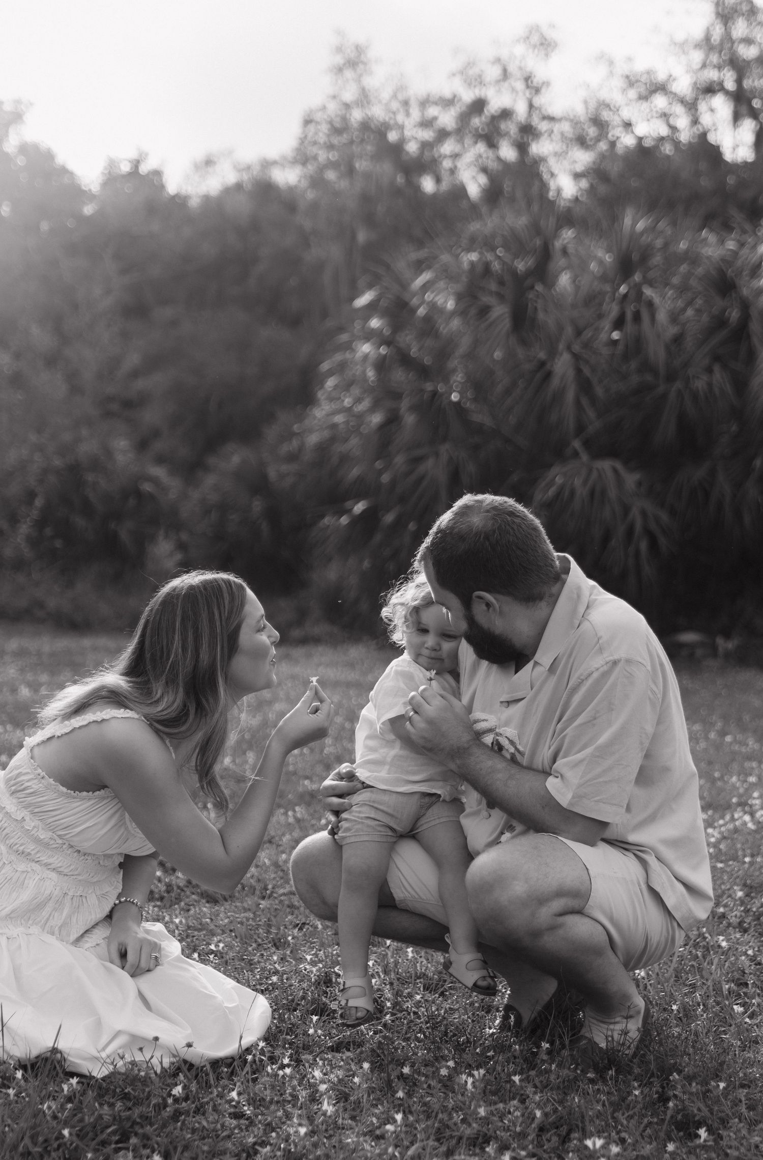 A couple sits together in a wildflower meadow at sunset in a series of romantic black and white photographs.