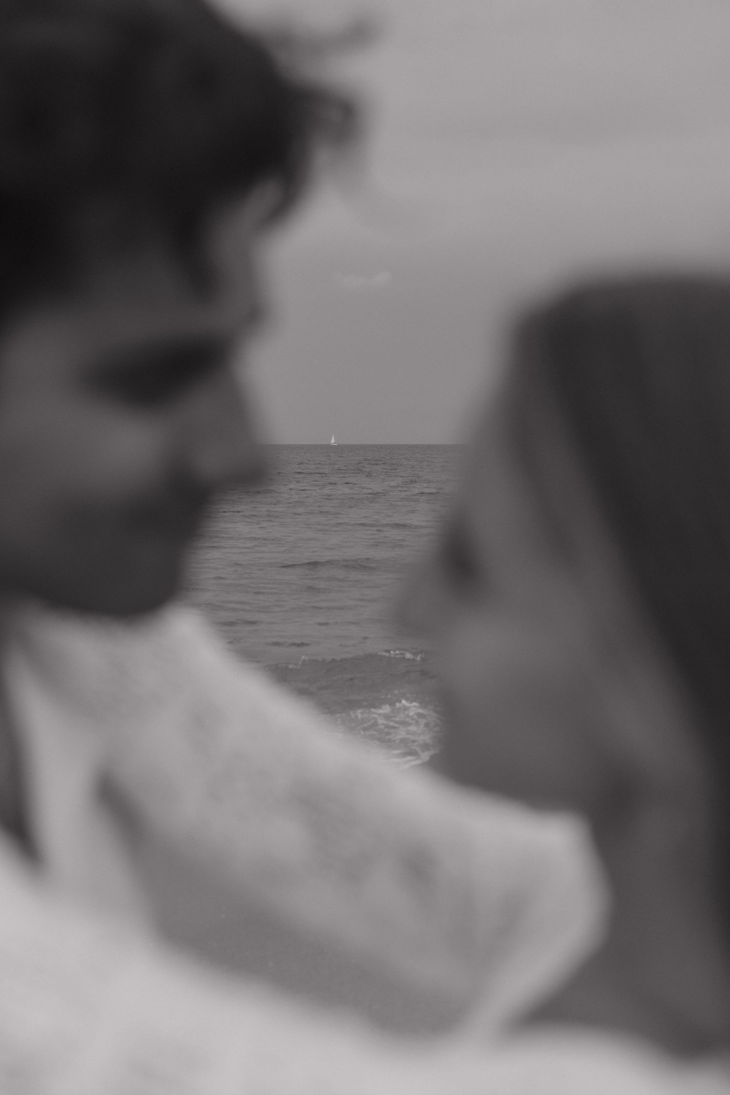 Black and white silhouettes against ocean horizon in romantic pose.