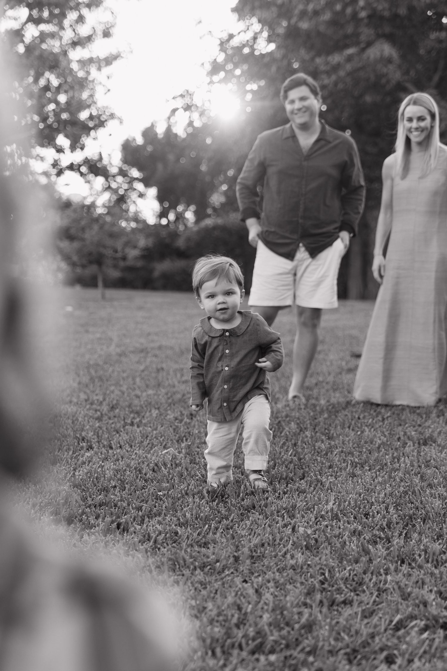 Family enjoying a playful moment together on grass during golden hour.