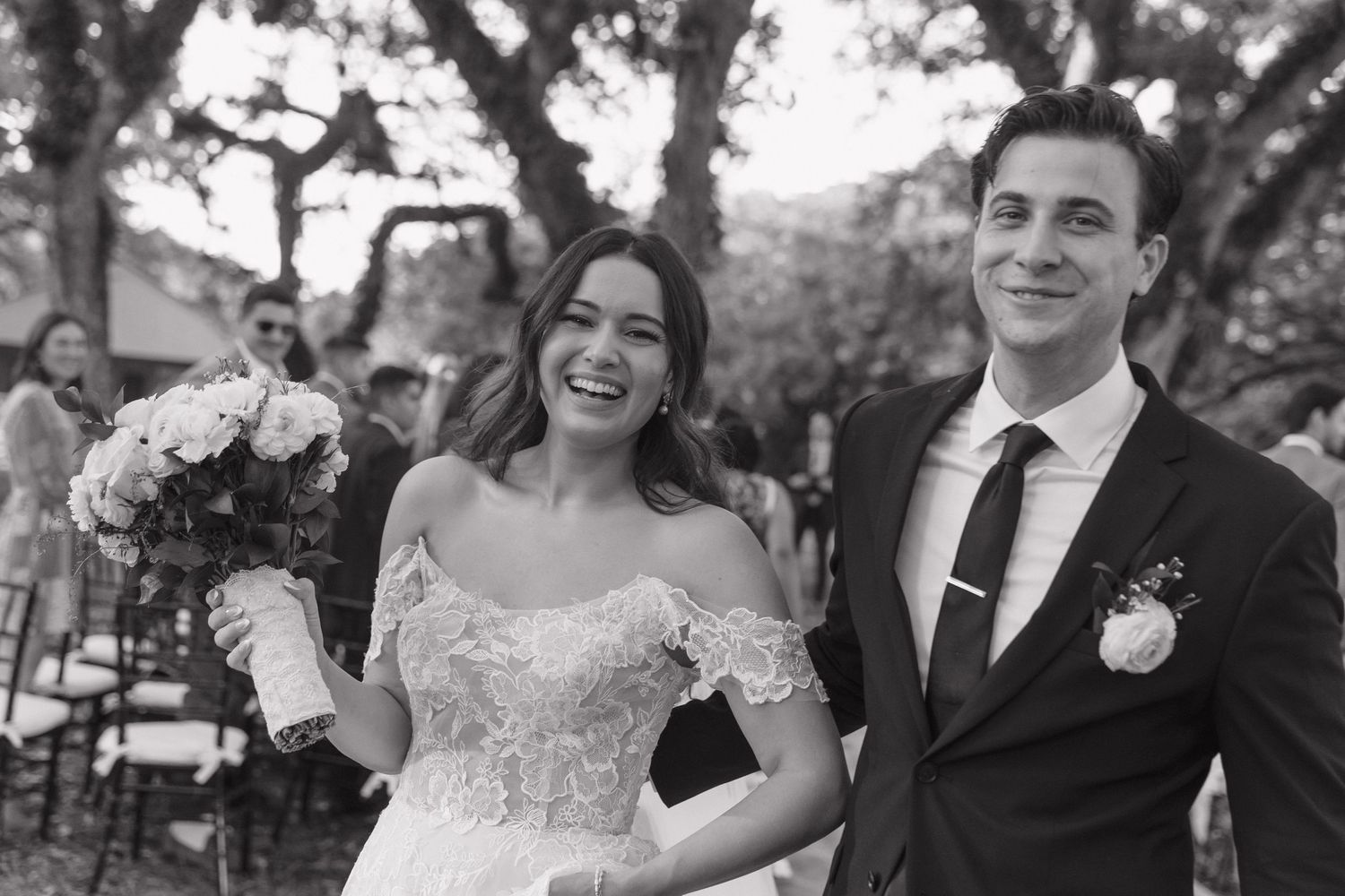 A wedding couple laughs together during their outdoor ceremony.