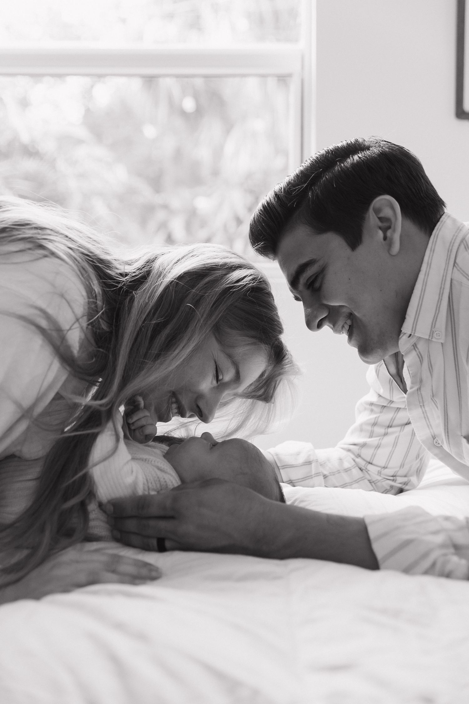 A series of black and white photos showing a couple sharing tender moments while lying together on a bed.