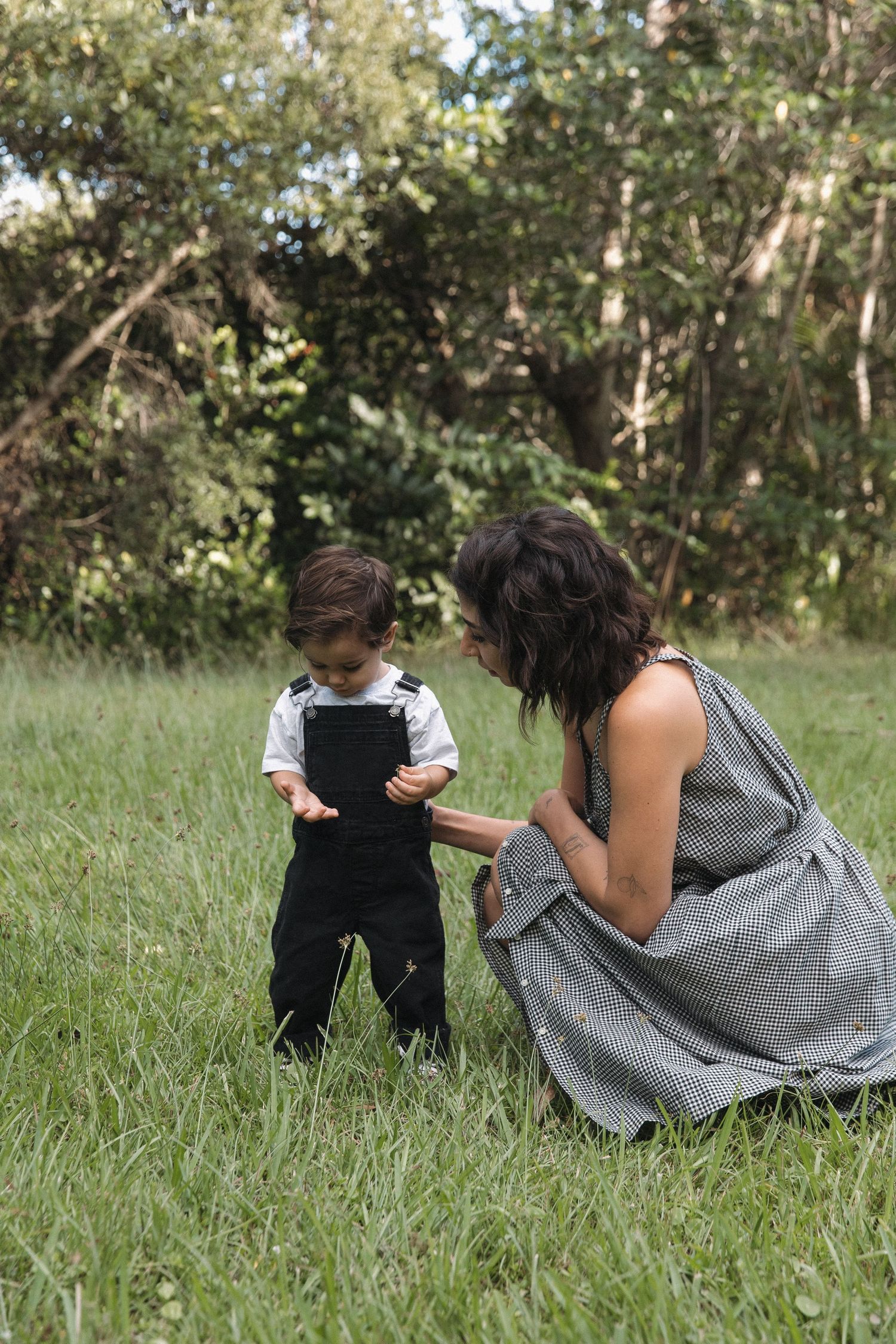 Sweet moment captured between parent and child laying in green grass outdoors.