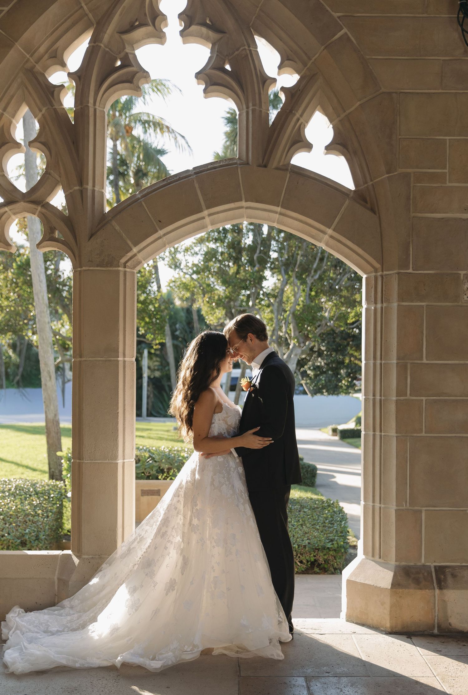 A couple sharing romantic moments under stone archways in an elegant outdoor wedding setting.