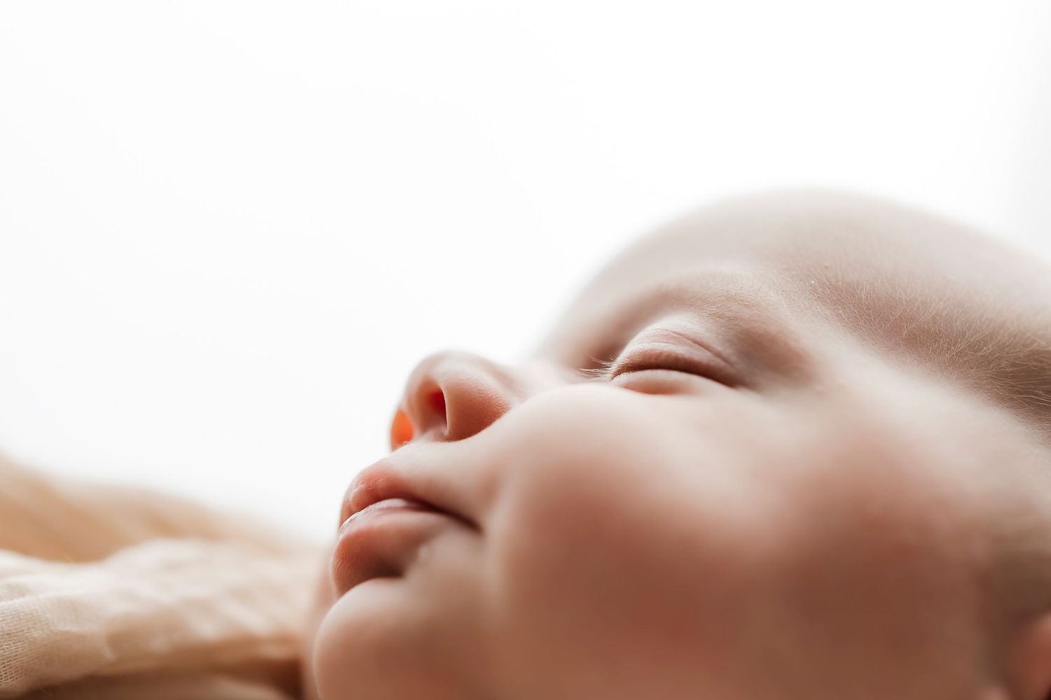 Serene sleeping newborn baby face in close-up with soft natural lighting.