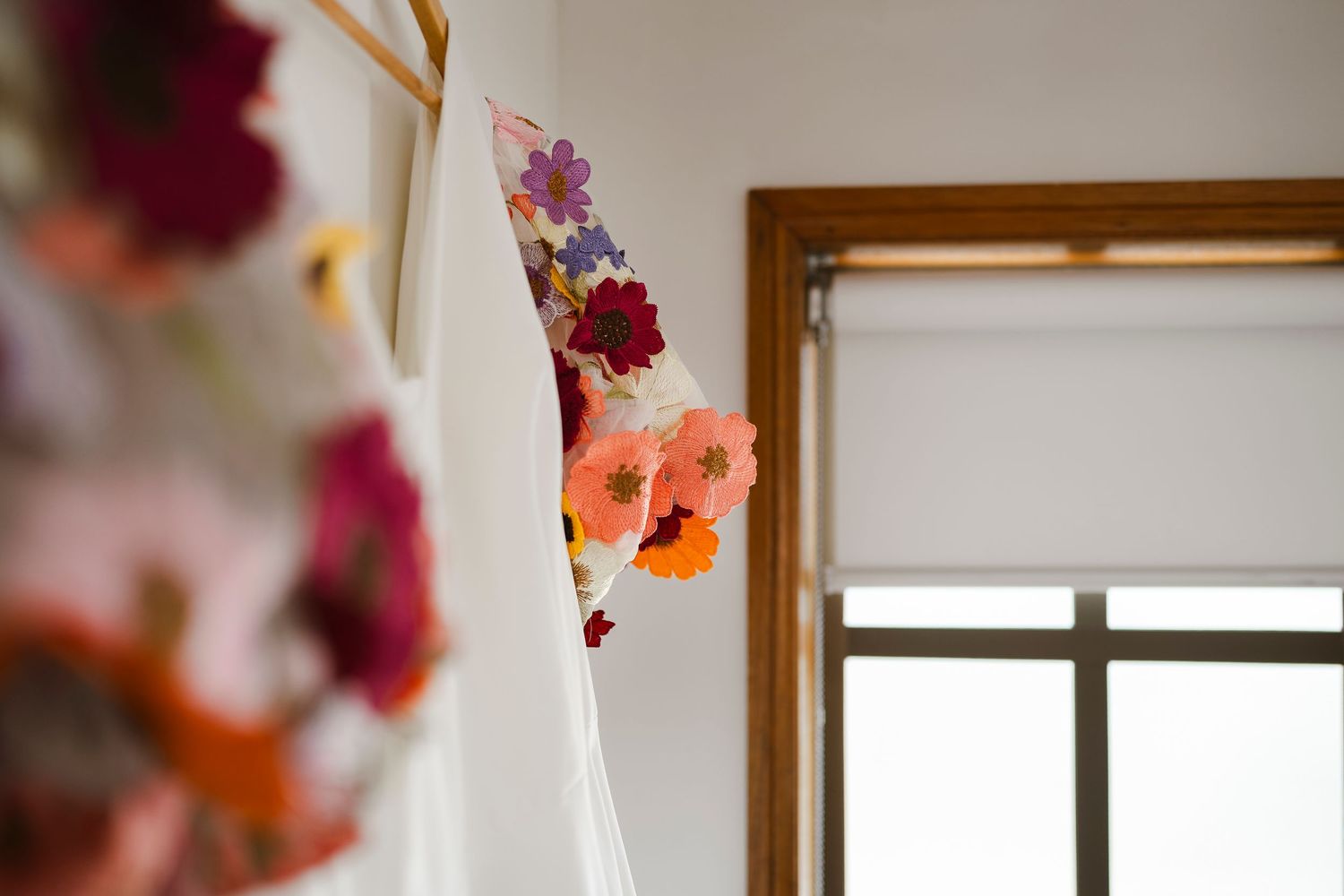 Colorful floral fabric banner with vibrant orange and purple flowers hanging near a bright window.